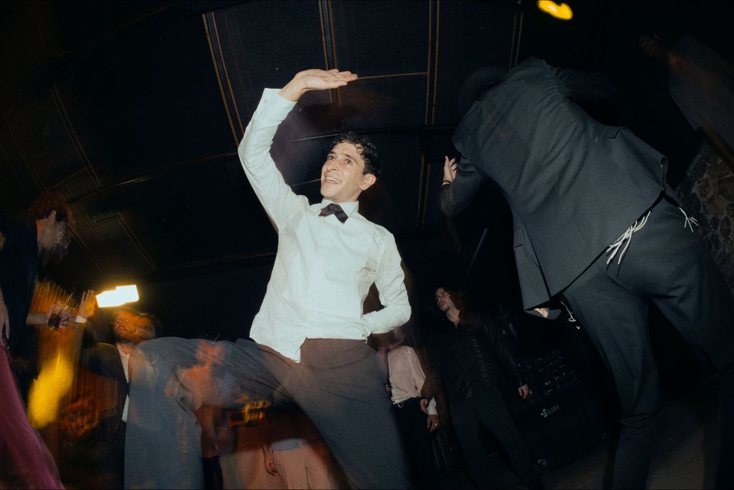 Guests dance and celebrate at a dimly lit indoor wedding reception.