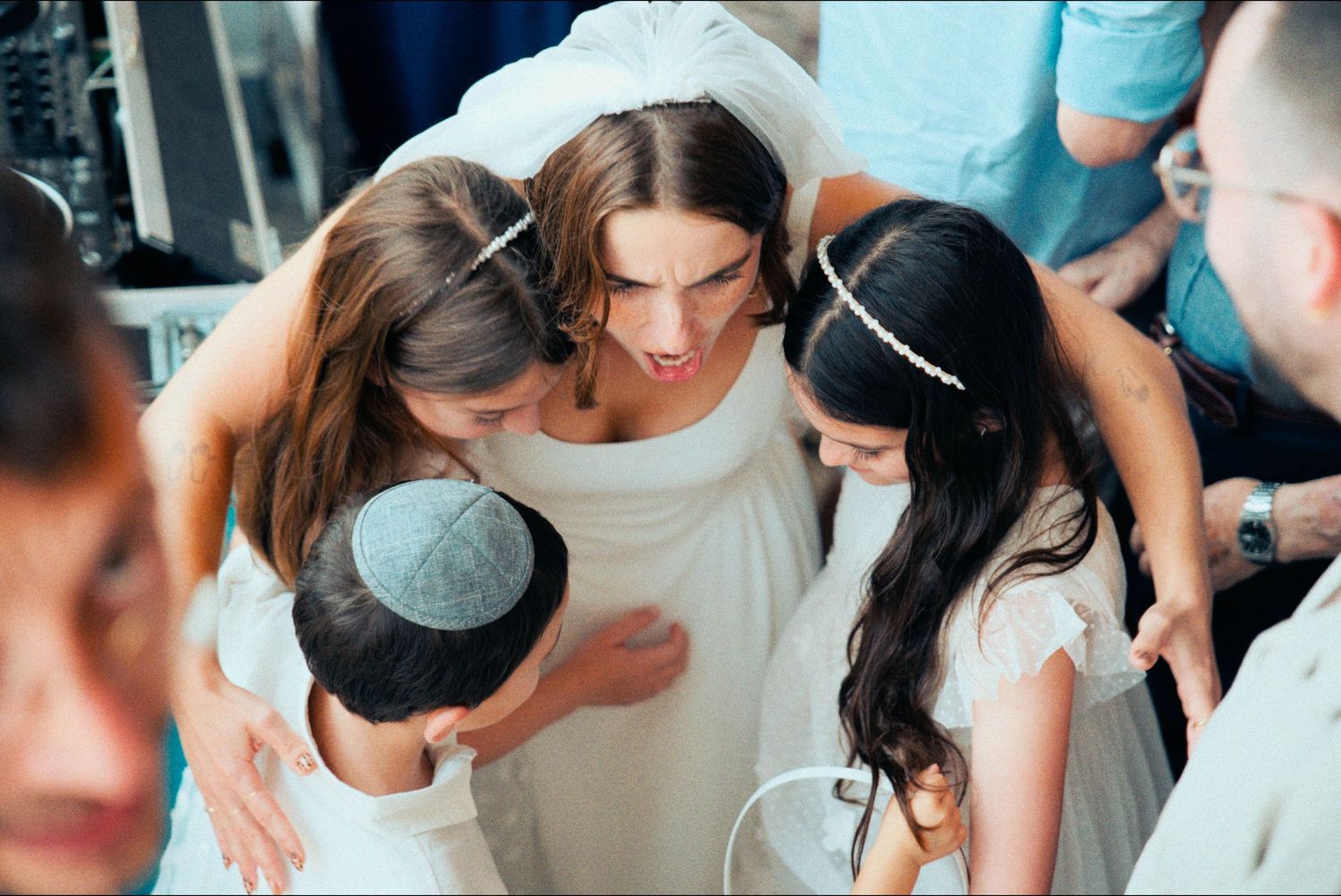 A group huddles together in an emotional moment during a wedding celebration.