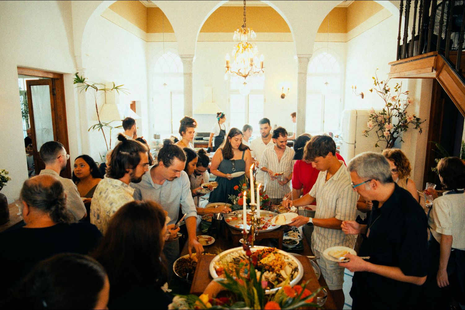 Panoramic view of an elegant reception hall with arched ceilings and chandeliers filled with celebrating guests.