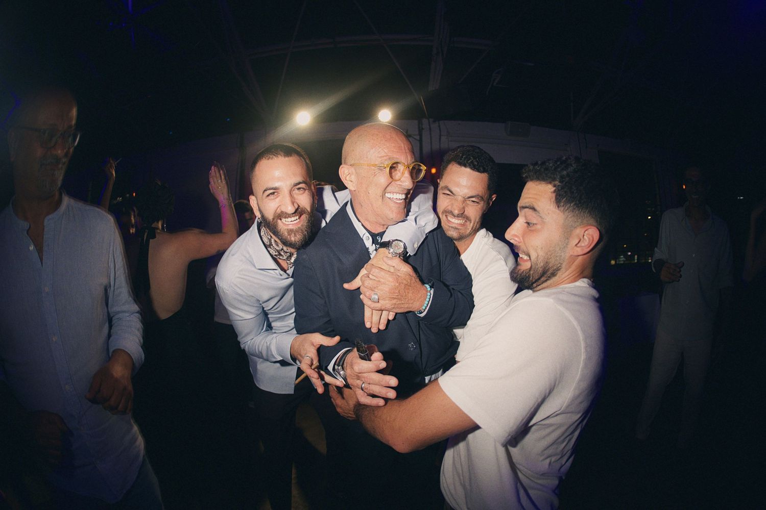 Group of men celebrating joyfully at a nighttime party event.