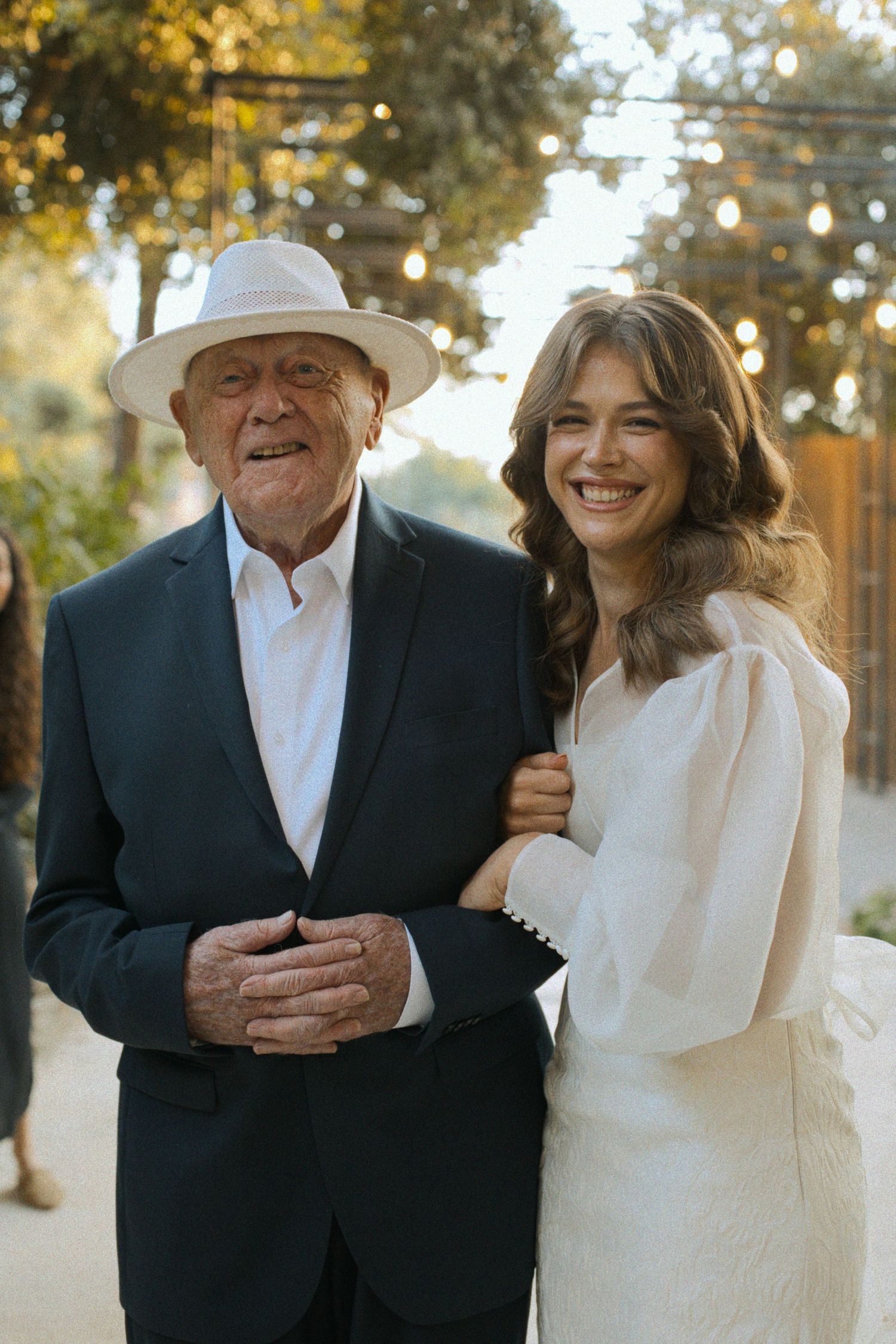 Outdoor portrait session featuring elegant formal attire and white sun hat.