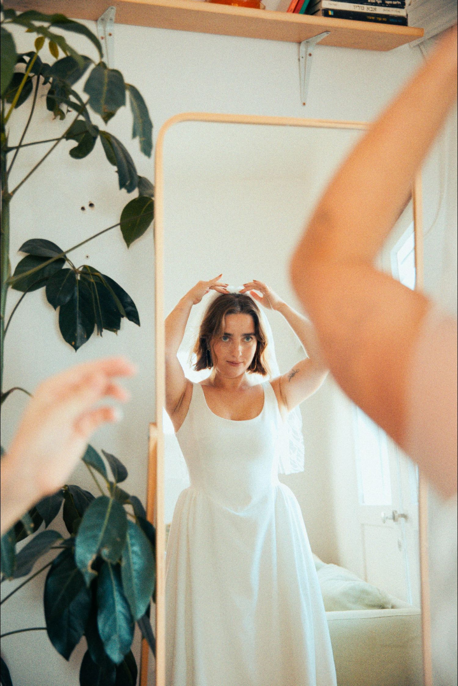 Woman in white dress moving dynamically in a room with large plants.