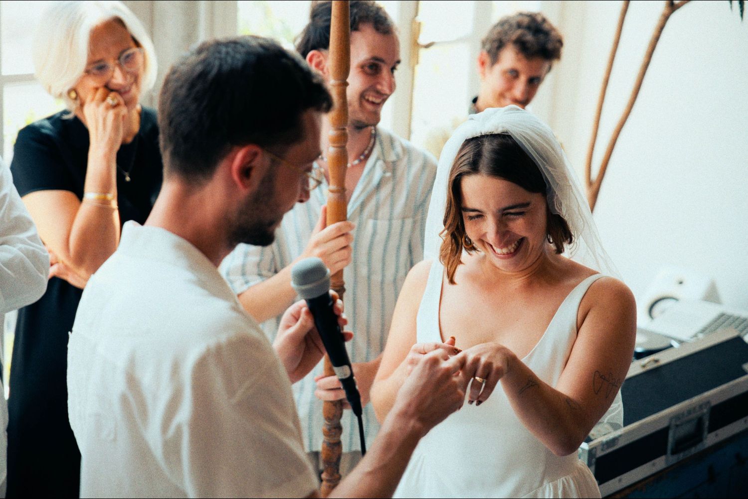 A couple shares a joyful moment during their wedding ceremony as guests look on.