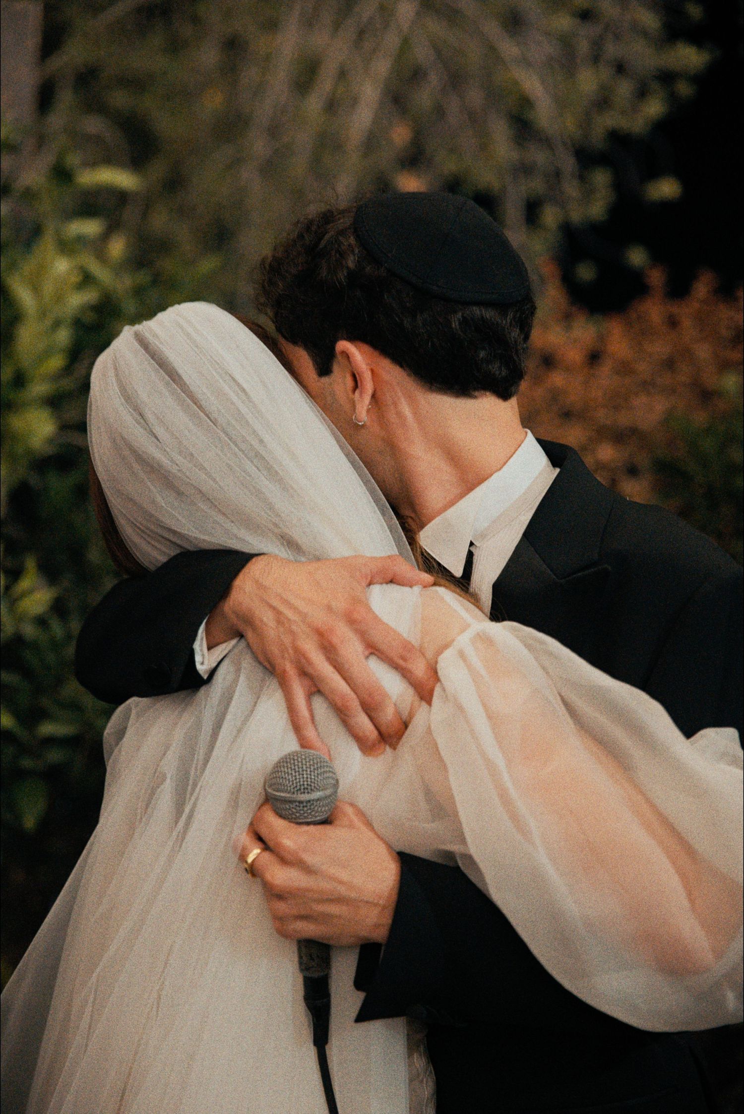 A romantic wedding kiss moment captured through a flowing white veil.