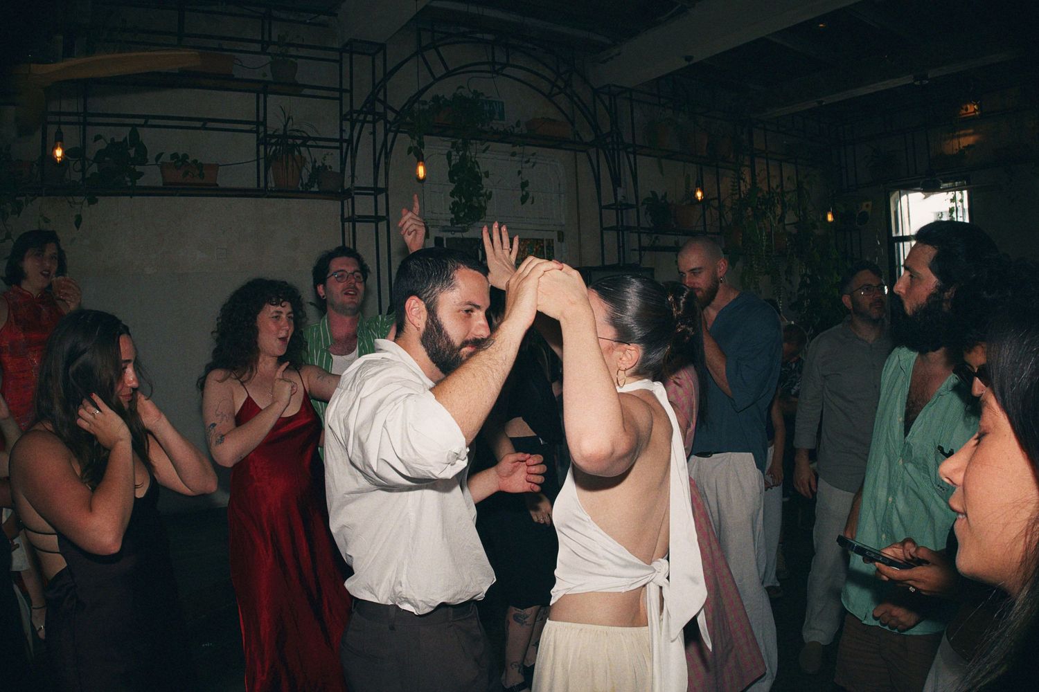Couple dancing together at a lively indoor wedding reception with guests celebrating in the background.
