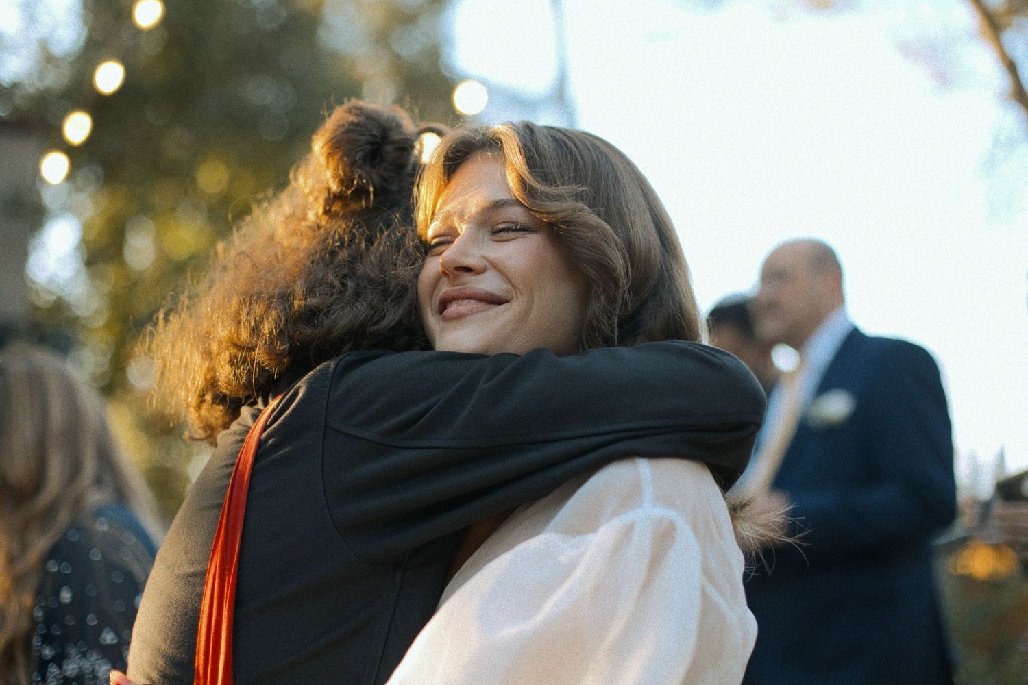 Joyful embraces shared between wedding attendees during outdoor sunset celebration.