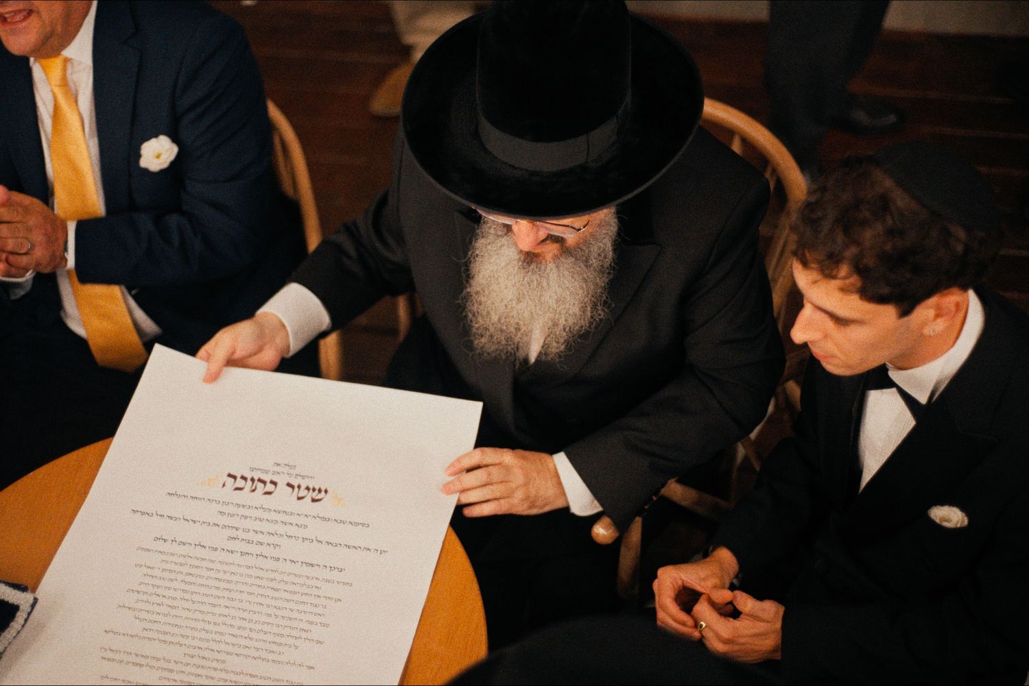 Traditional Jewish wedding ceremony with ketubah signing and black hats.