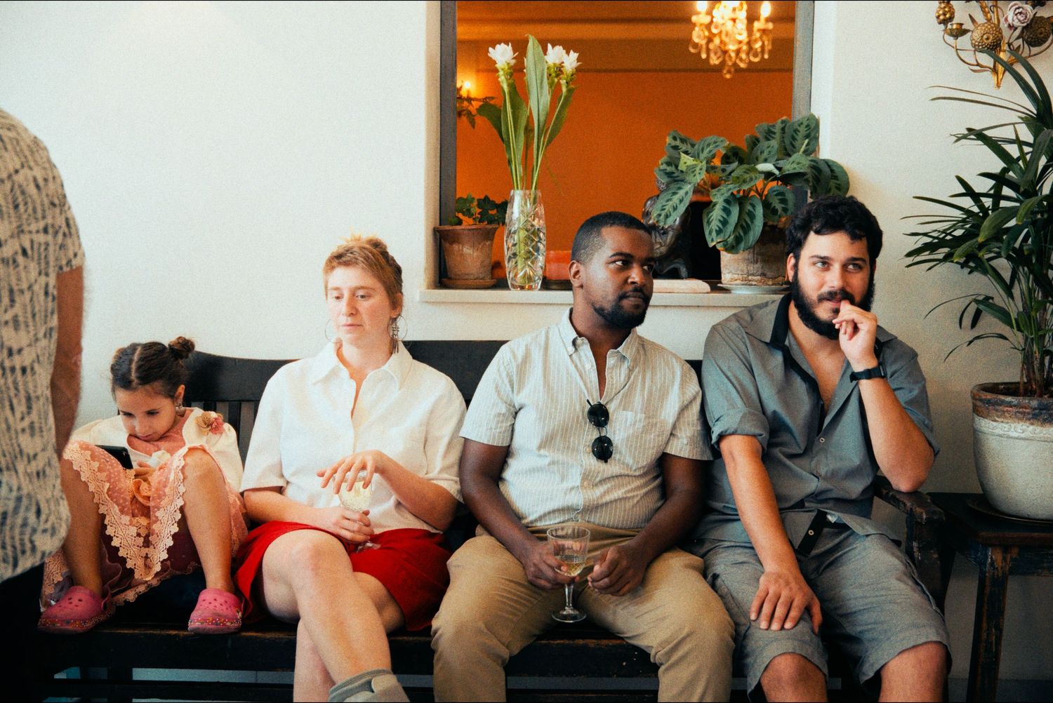 Diverse group of guests seated on a bench at a social gathering.