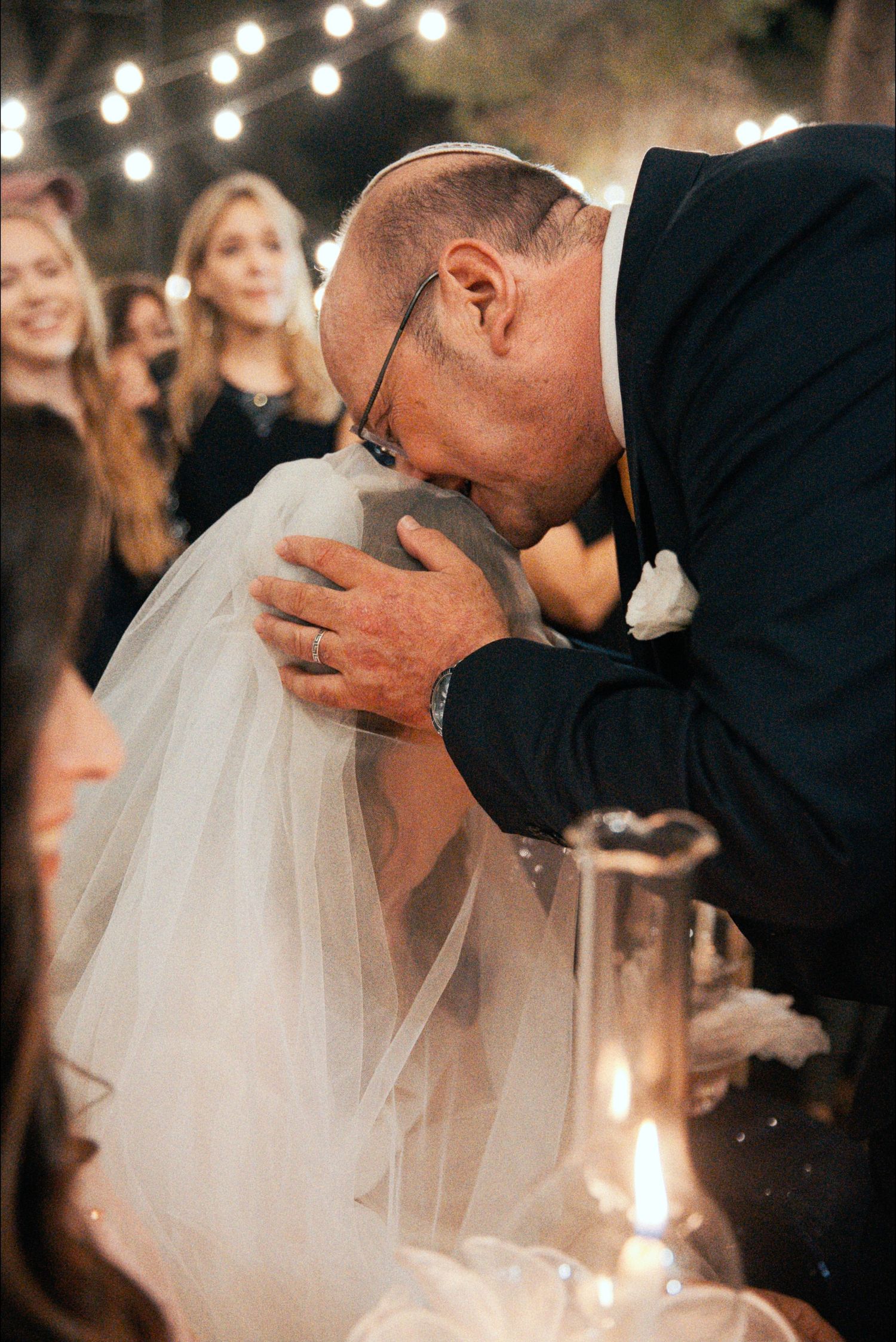 A tender moment between newlyweds during their wedding reception under string lights.