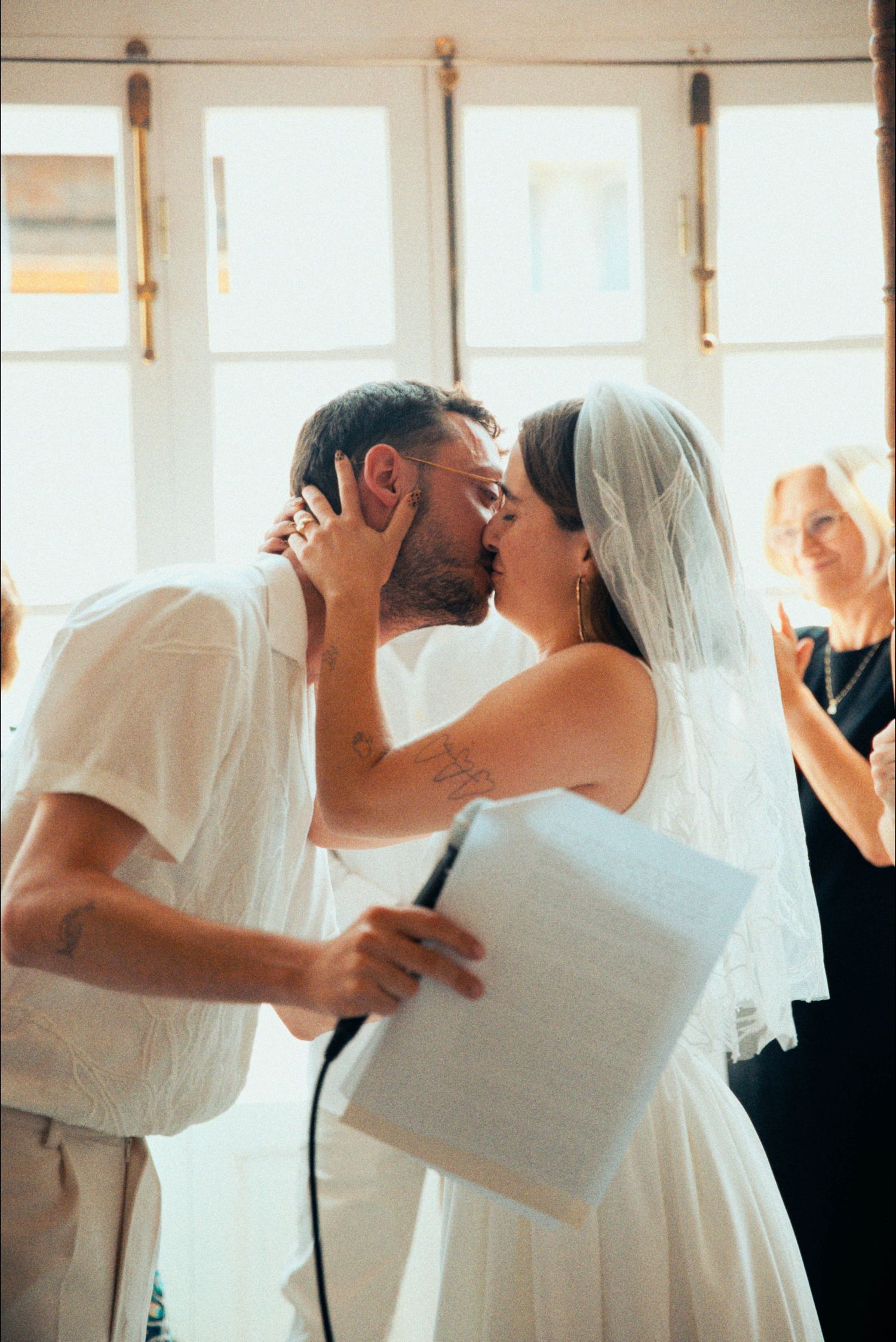 Romantic dance moment at a wedding celebration with natural light streaming through windows.