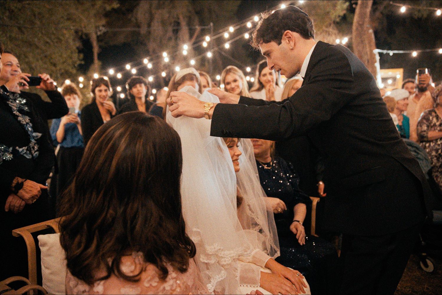 Evening wedding celebration with string lights and dancing guests.