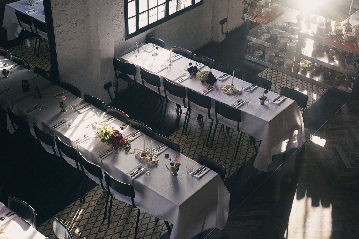 Elegant restaurant dining room with white tablecloths, set tables, and natural light streaming through large windows.