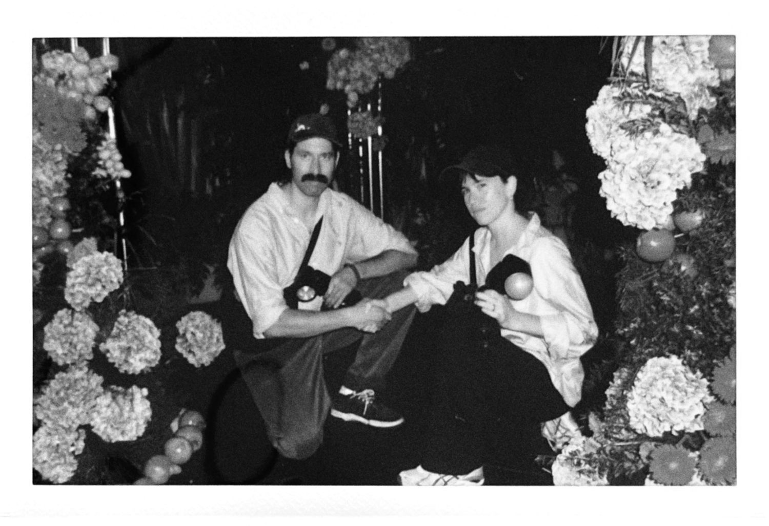 Black and white photo of a man and woman sitting outdoors surrounded by blooming hydrangea flowers.
