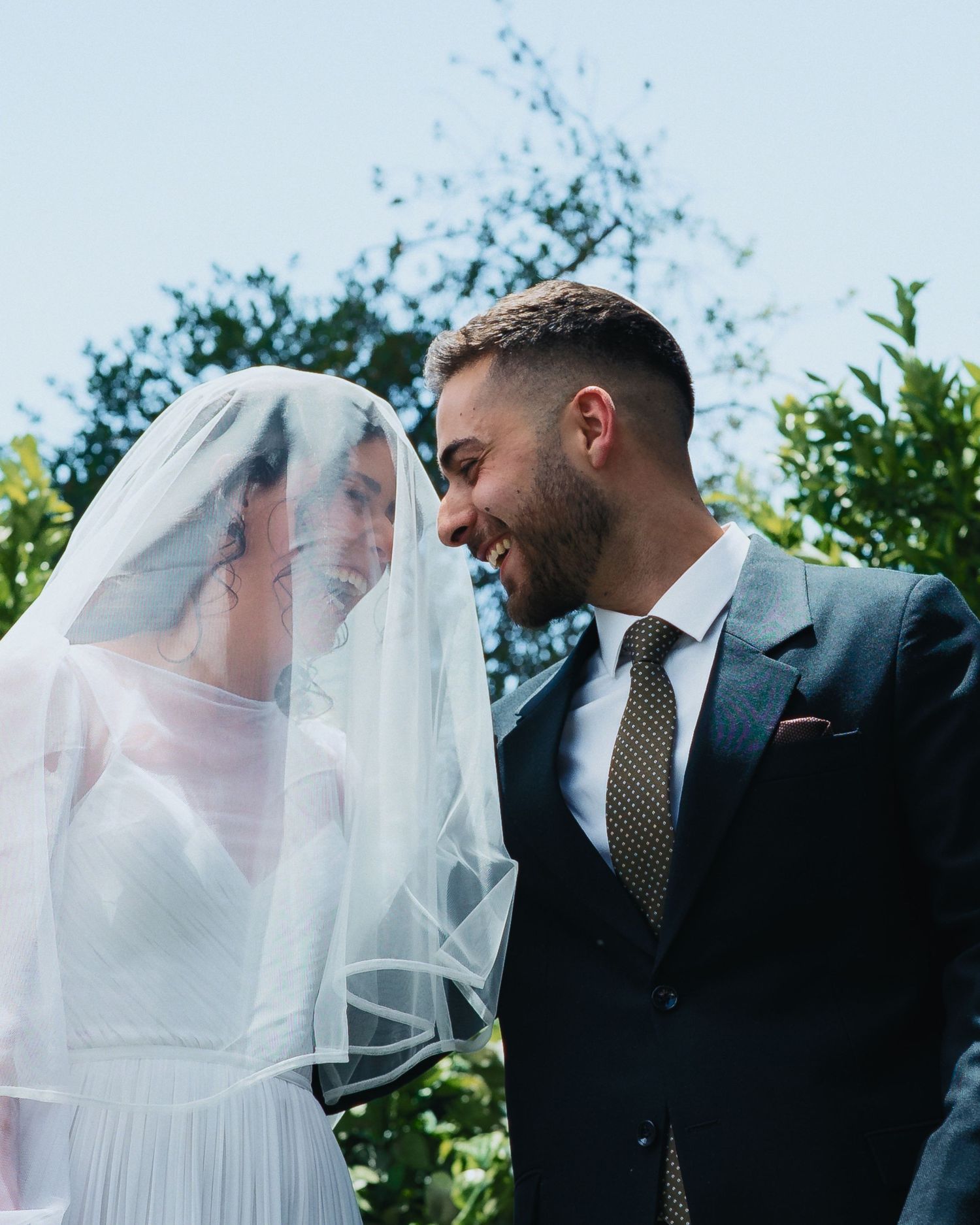 A romantic wedding moment captured outdoors with a flowing white veil.