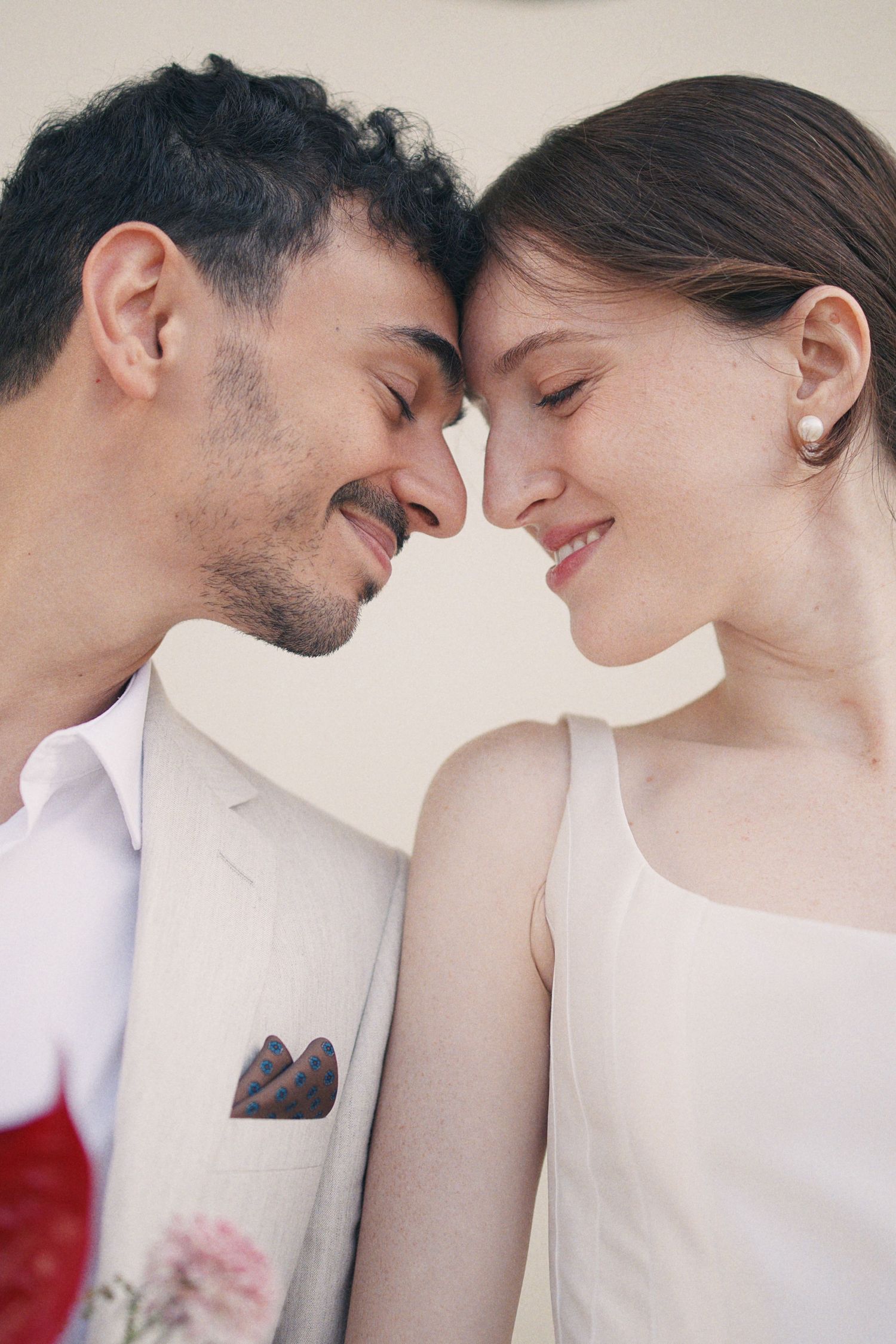 Close-up of smiling bride and groom touching foreheads in tender wedding portrait.