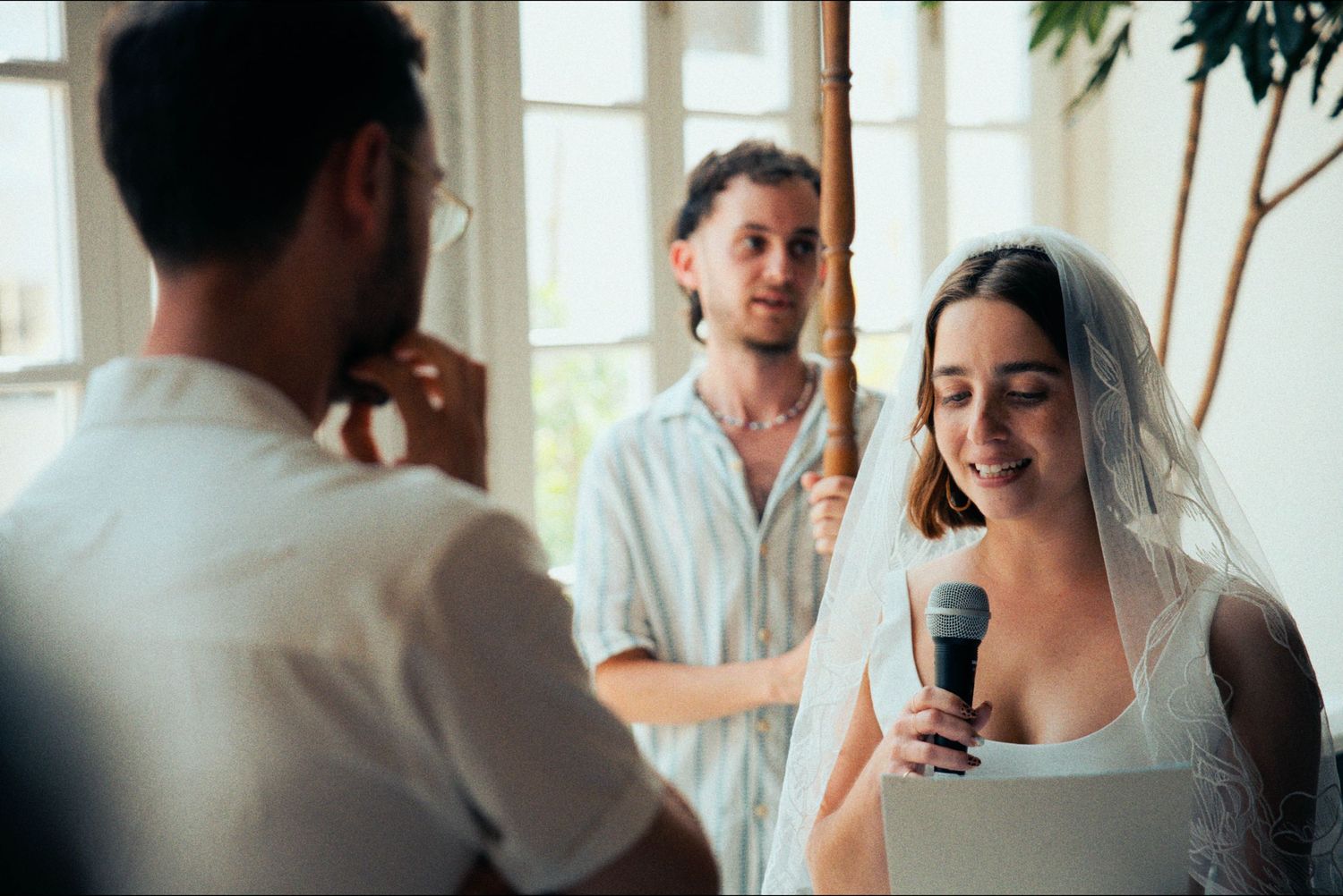 Guests celebrating at an elegant indoor wedding reception with natural lighting.