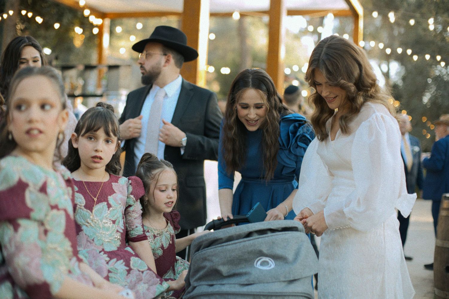 Wedding celebration with string lights and guests mingling at an outdoor evening reception.