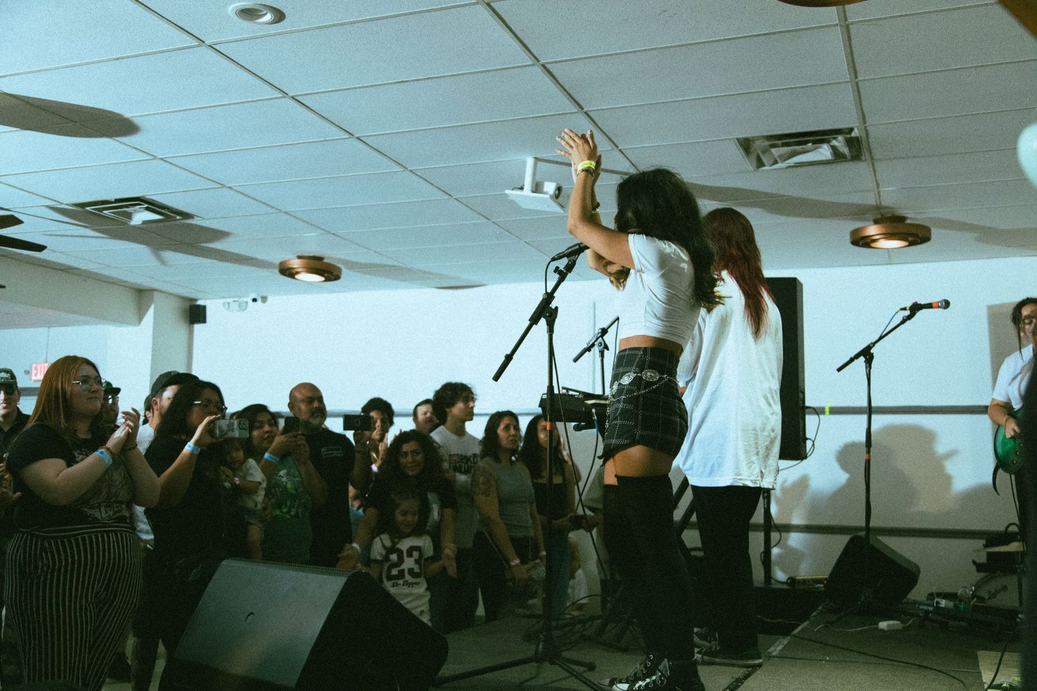 Energetic performer on stage engaging with crowd during indoor concert performance.