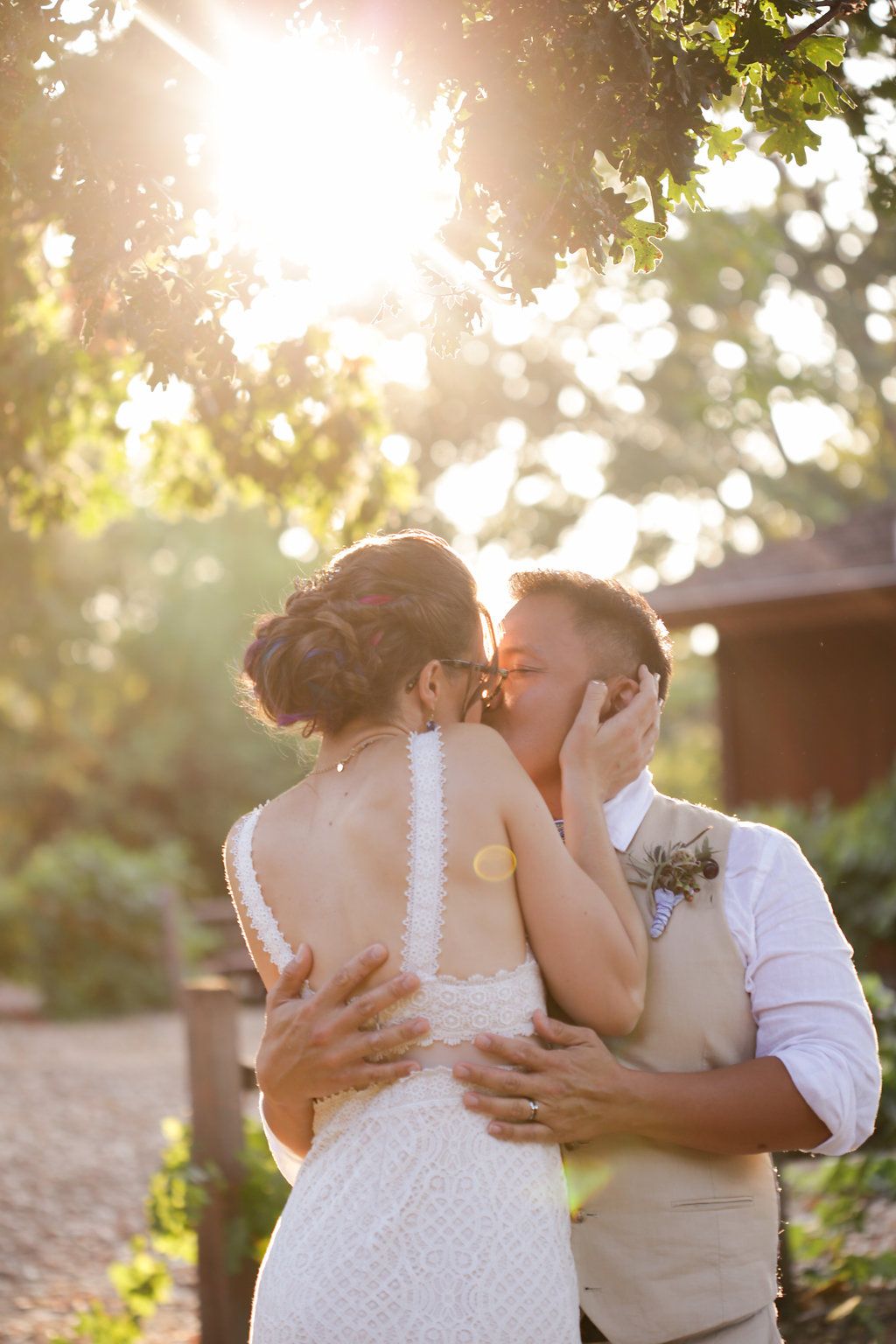 A sun-drenched wedding portrait with golden light filtering through trees.