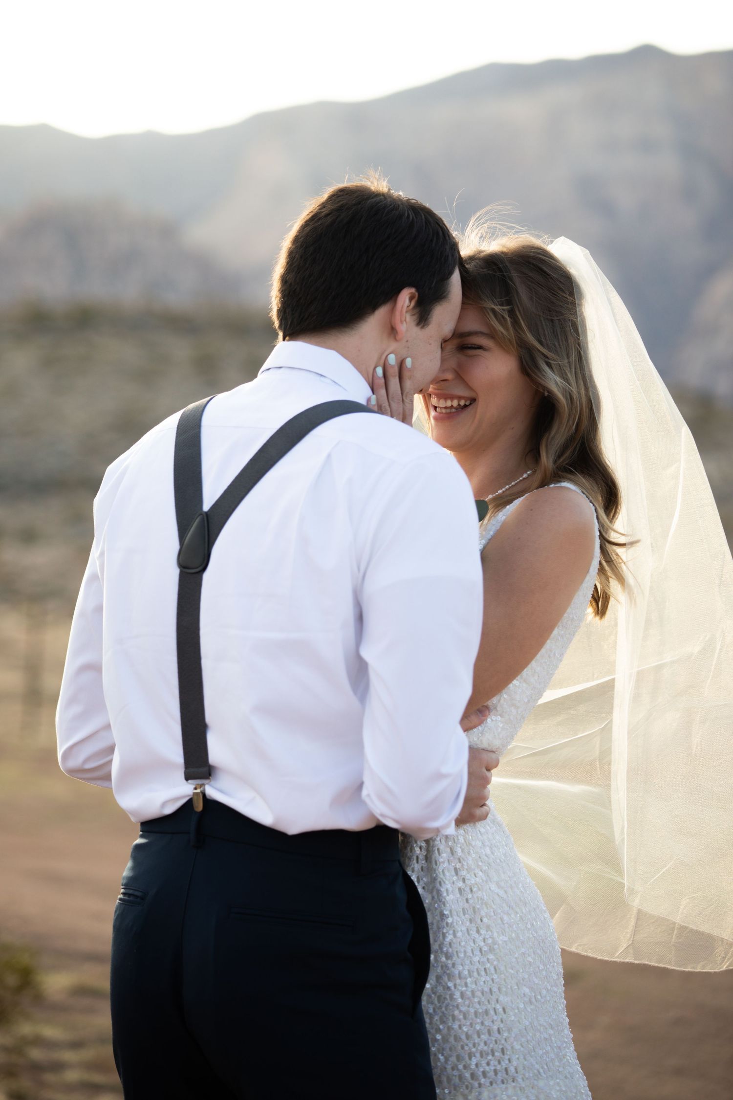A tender wedding moment set against a backdrop of majestic mountains at sunset.