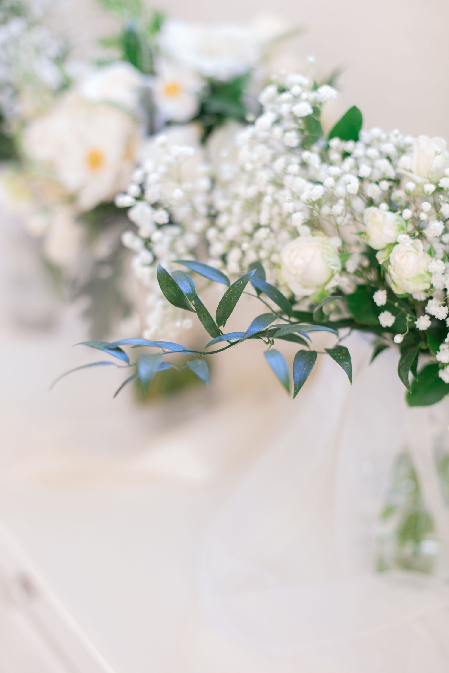Delicate white floral arrangement with baby's breath and greenery in soft focus.