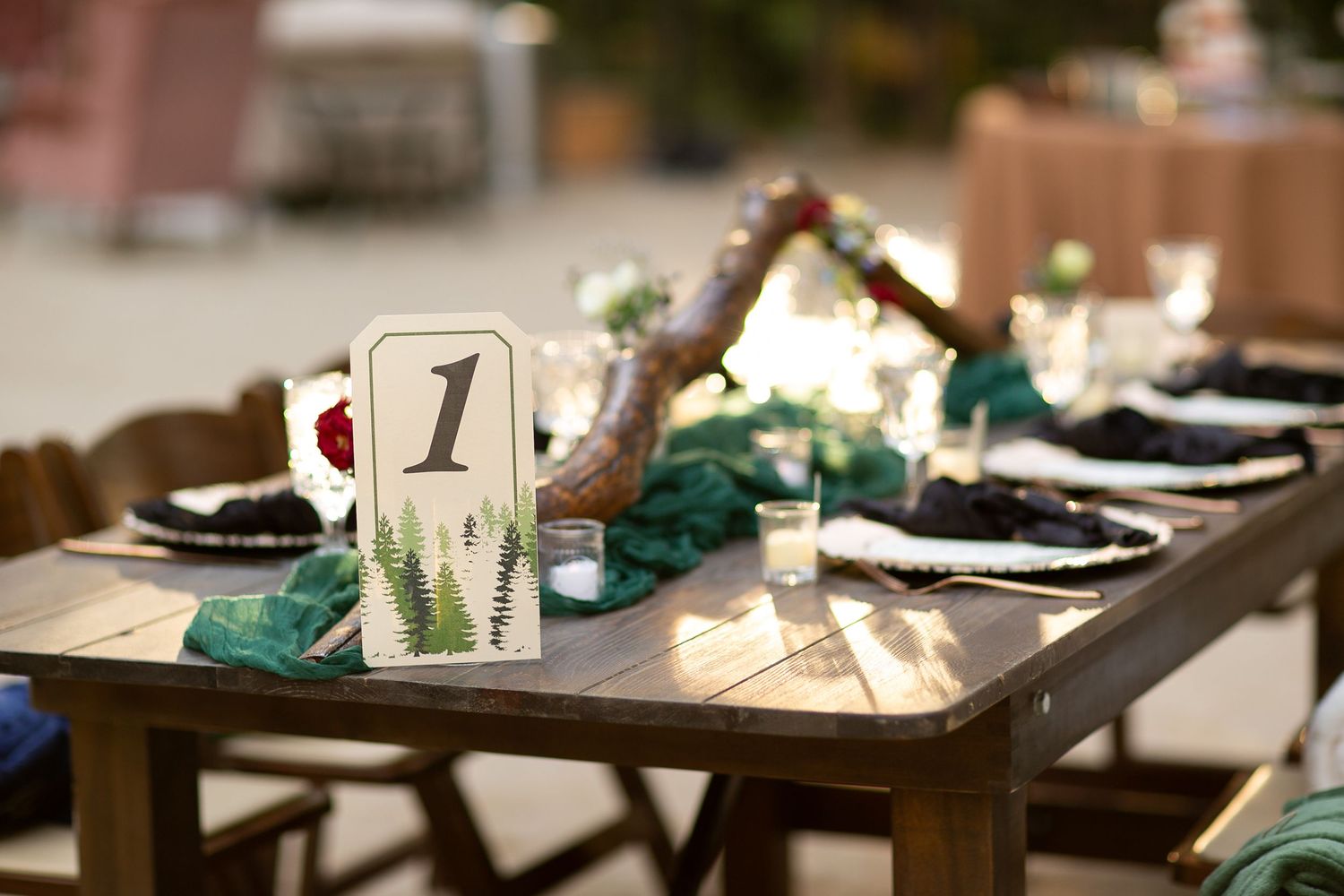 Rustic wedding table setting with table number one card, black plates and teal accents.
