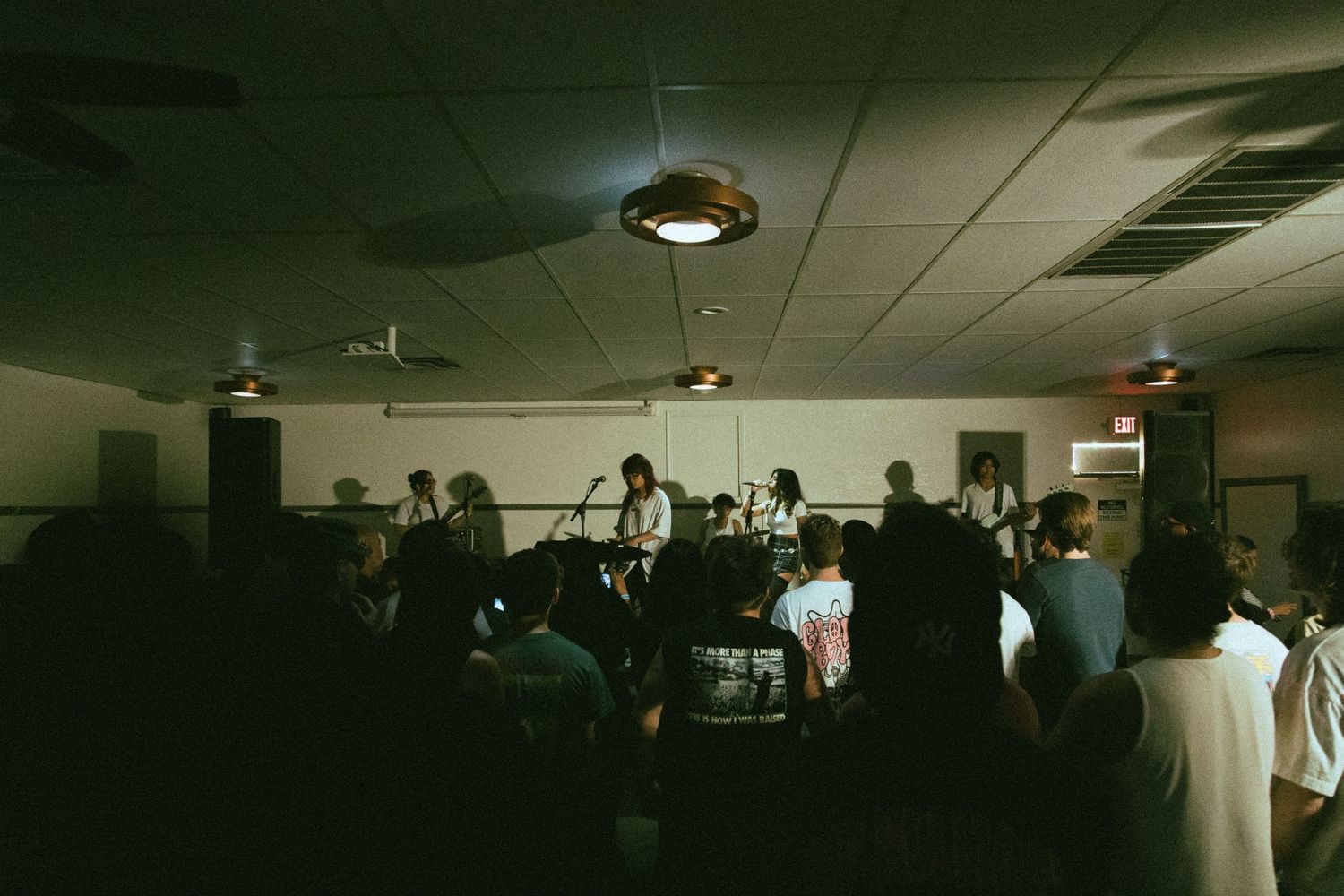 Musicians perform on stage in a dimly lit indoor venue.