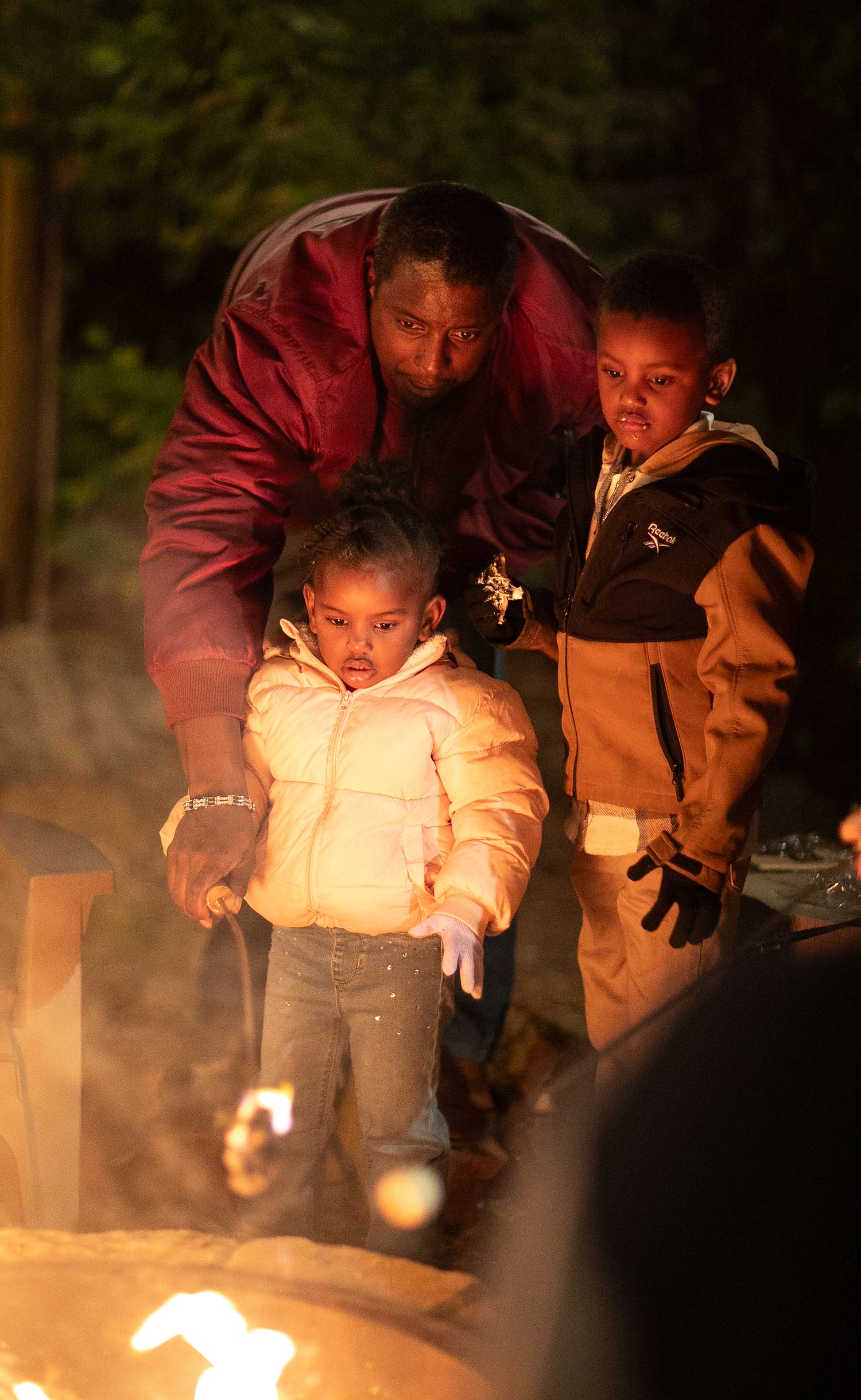 Guests gathered around a warm fire at an outdoor nighttime event.