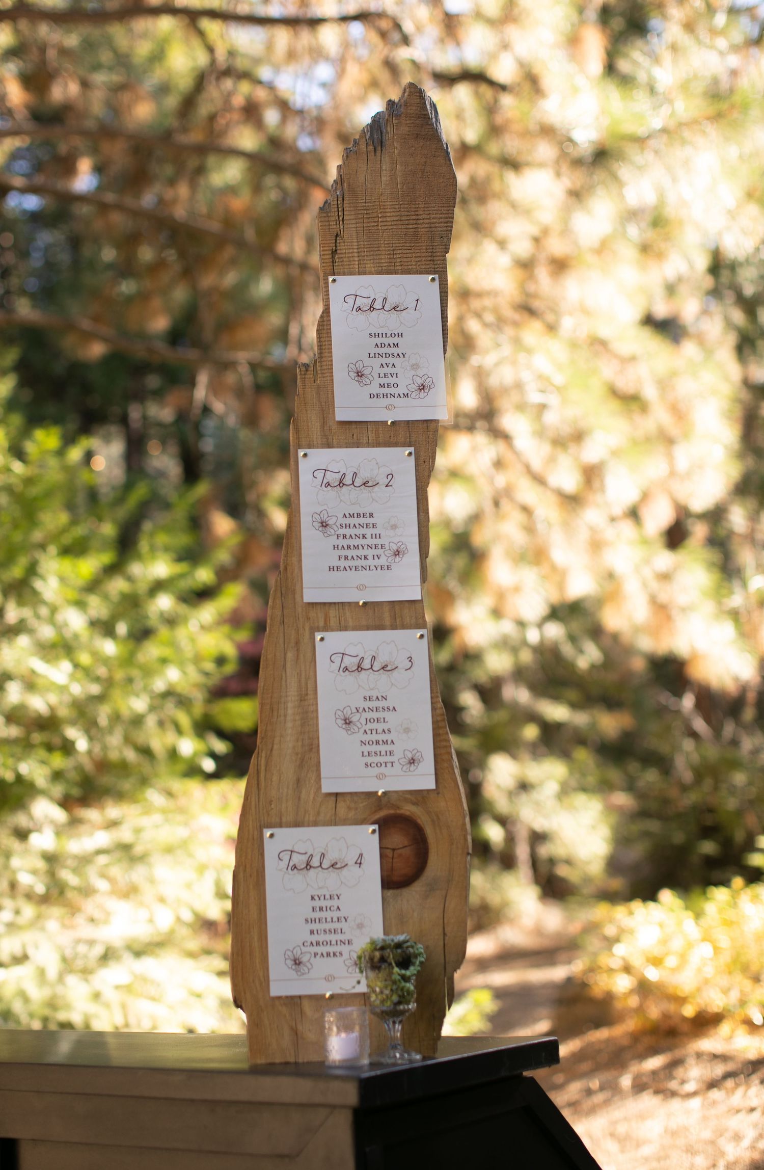 Wooden post displaying multiple table assignment cards for event seating.