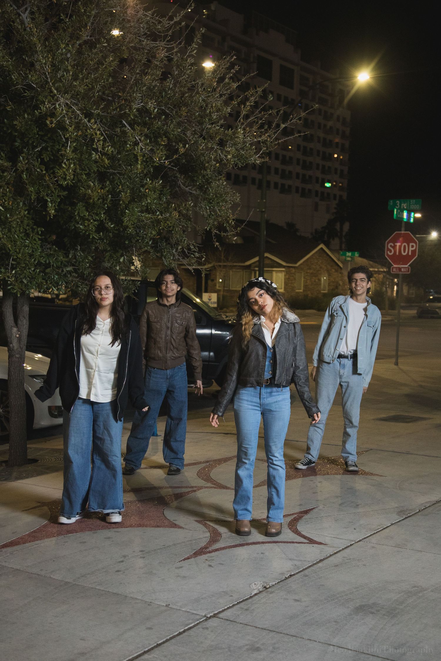 Group poses together outdoors at night on a city sidewalk.