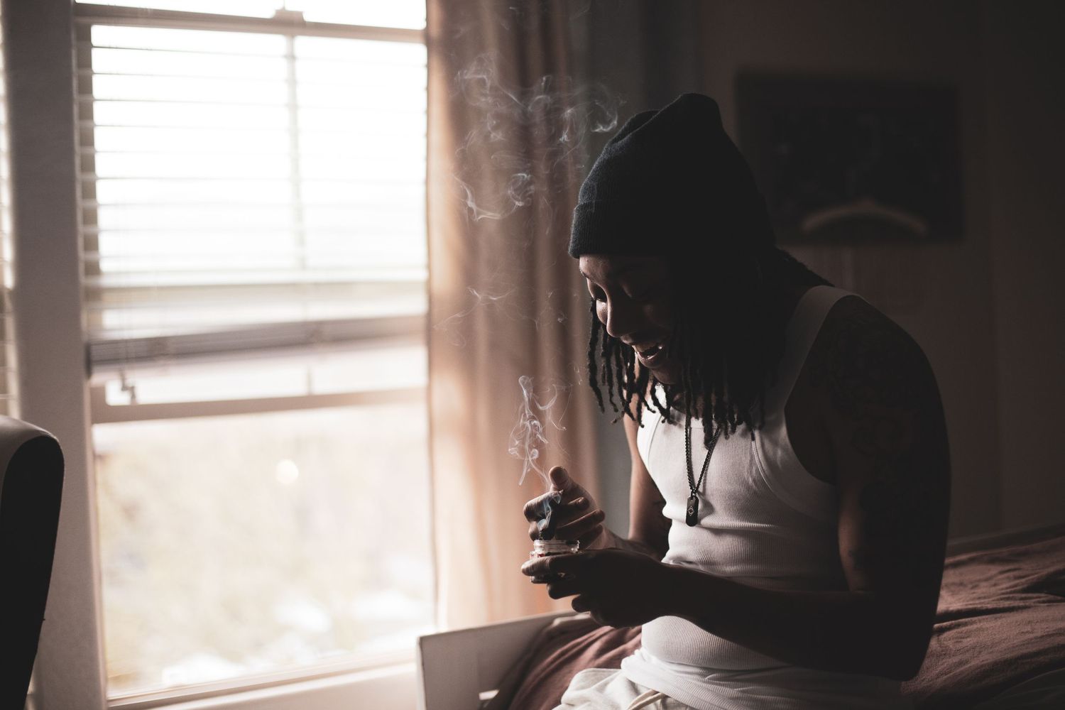 Sunlight streams through windows in a dimly lit bedroom creating a moody atmosphere.