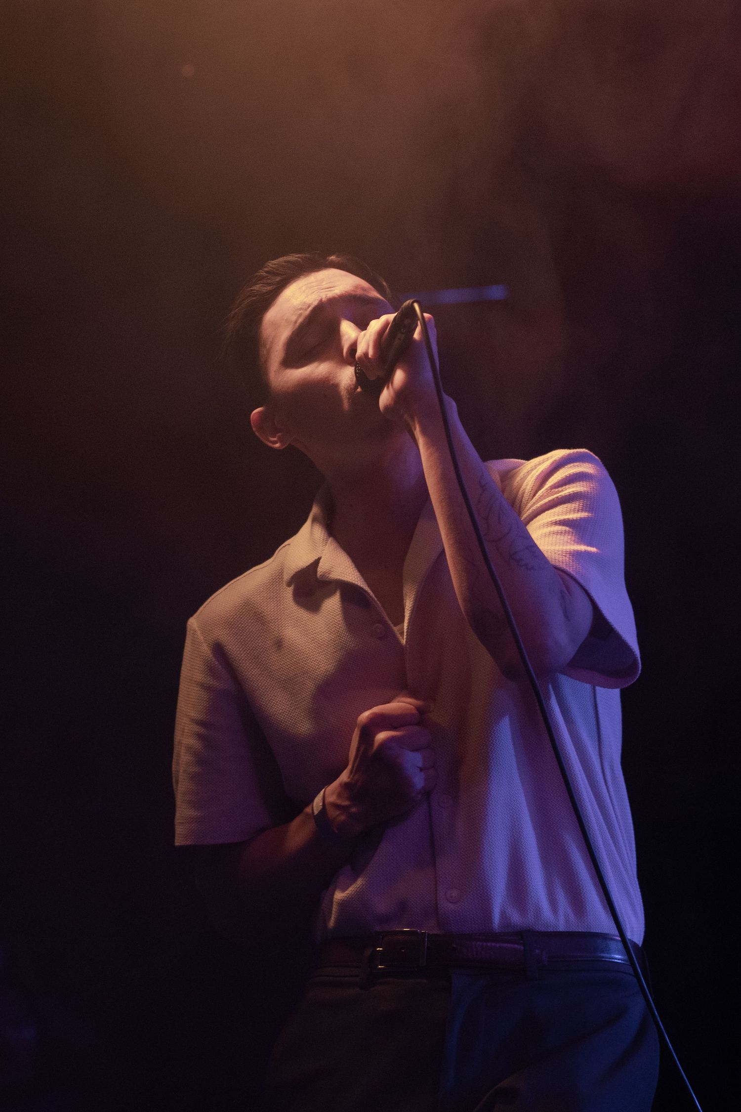 Singer performs emotively in dramatic side lighting during concert.