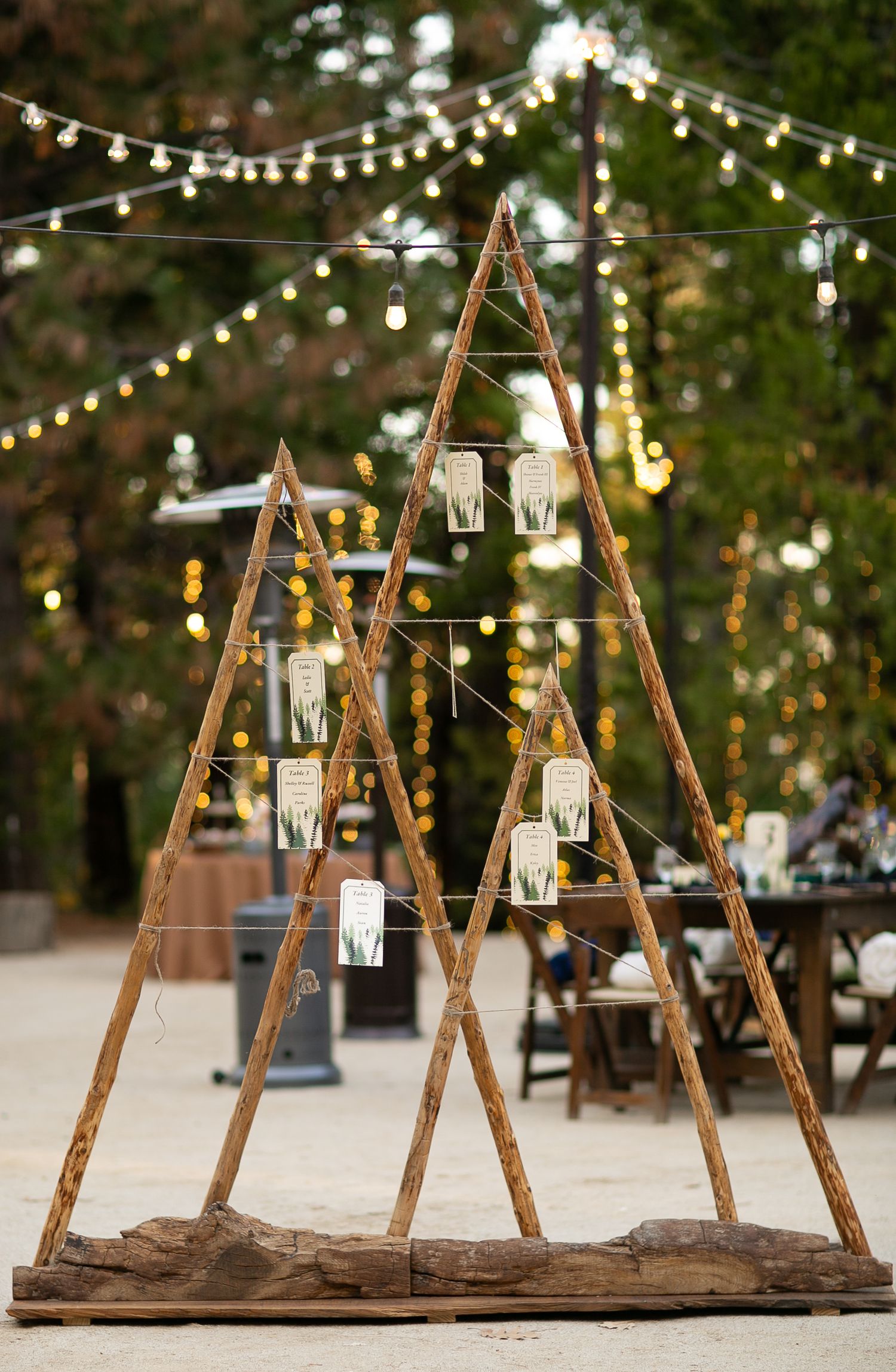 Wooden A-frame display structure with hanging mason jar lights and string lighting backdrop.