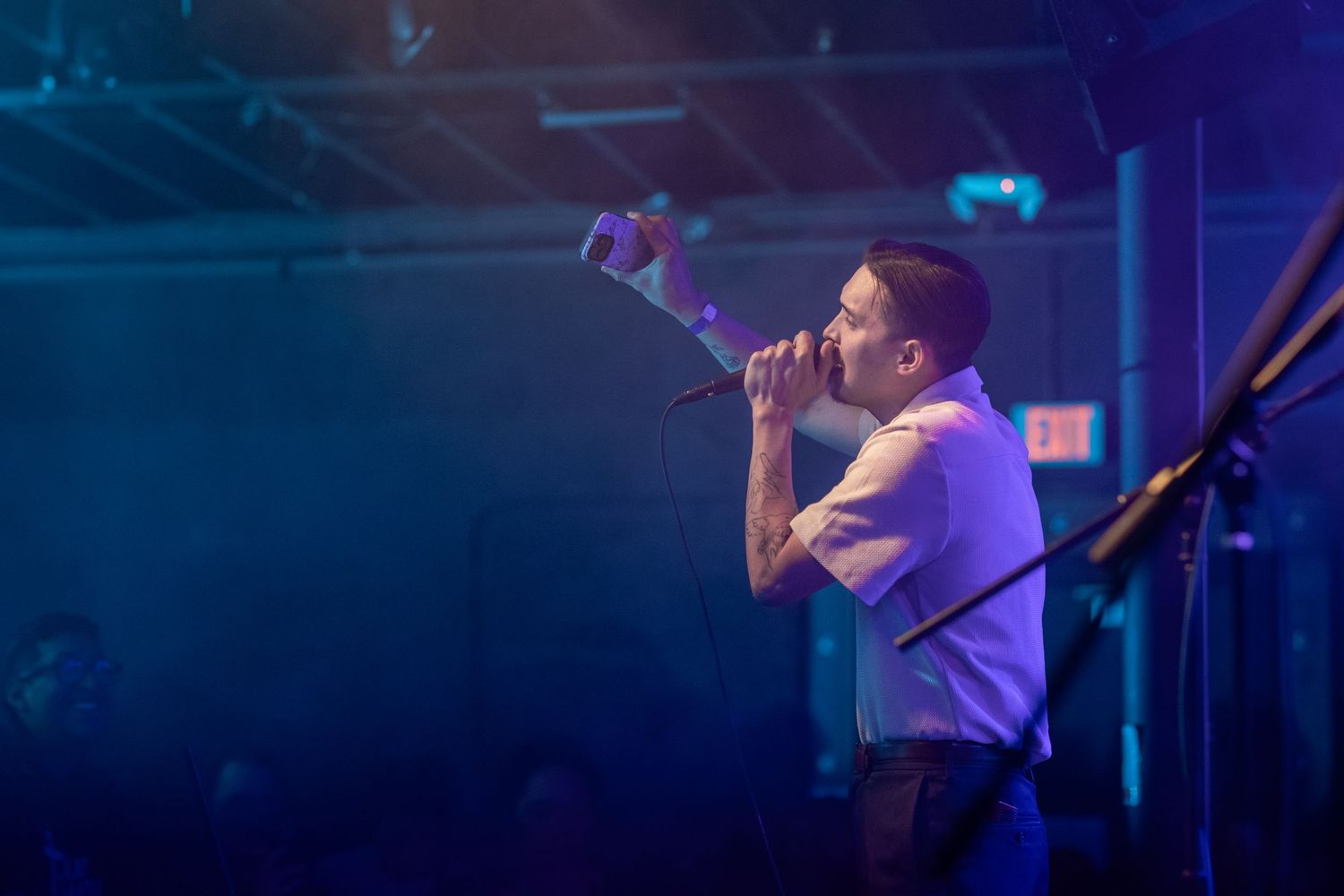 Singer performing passionately on stage with blue atmospheric lighting.