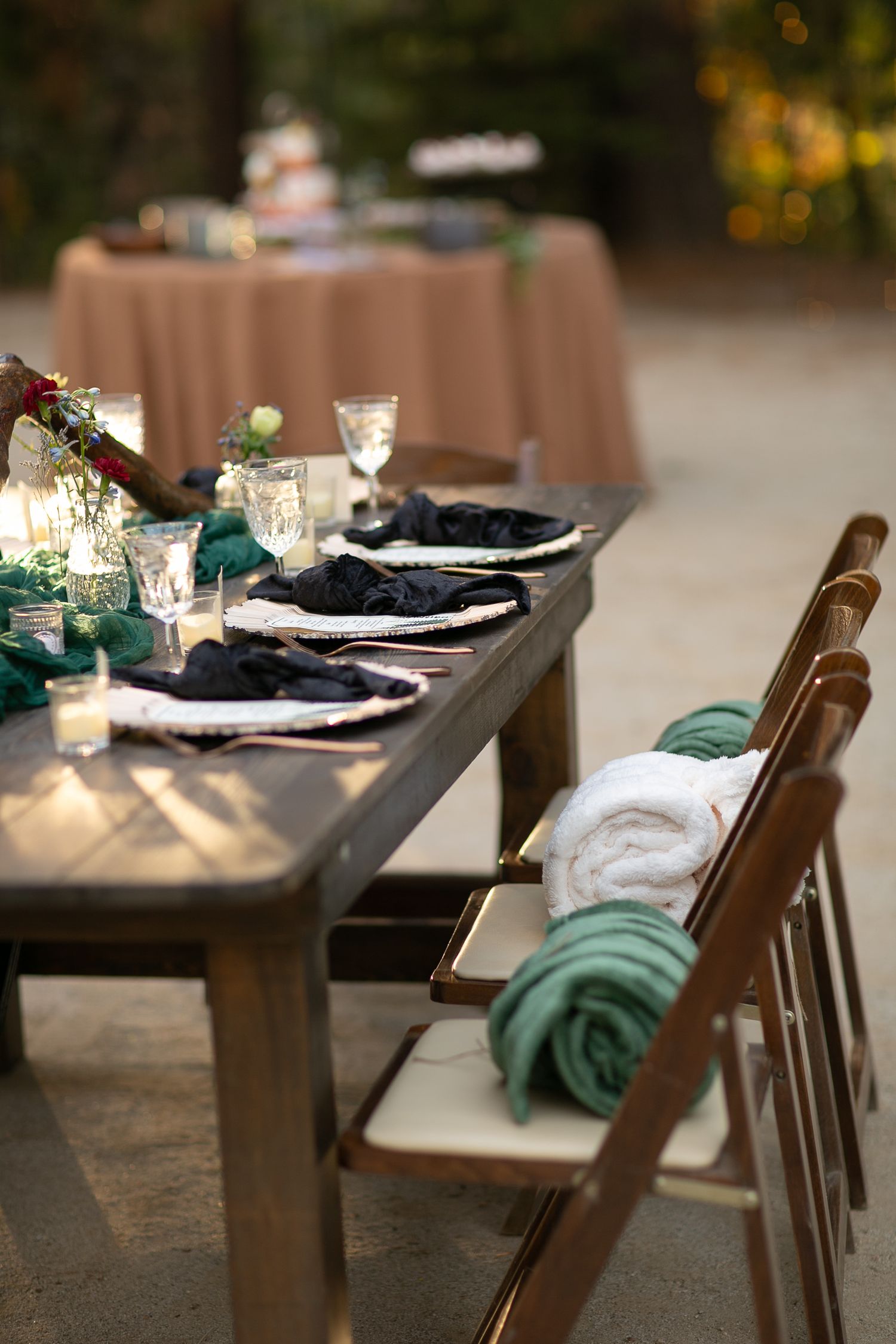 Long wooden table with formal place settings featuring black napkins and teal accents.