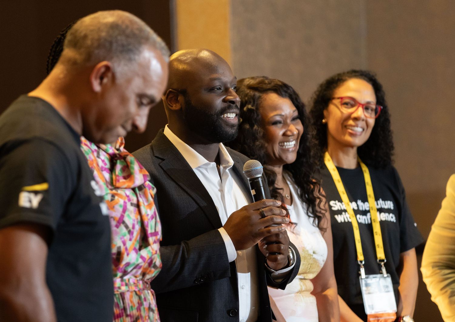 Group of speakers sharing a microphone on stage at a professional conference event.