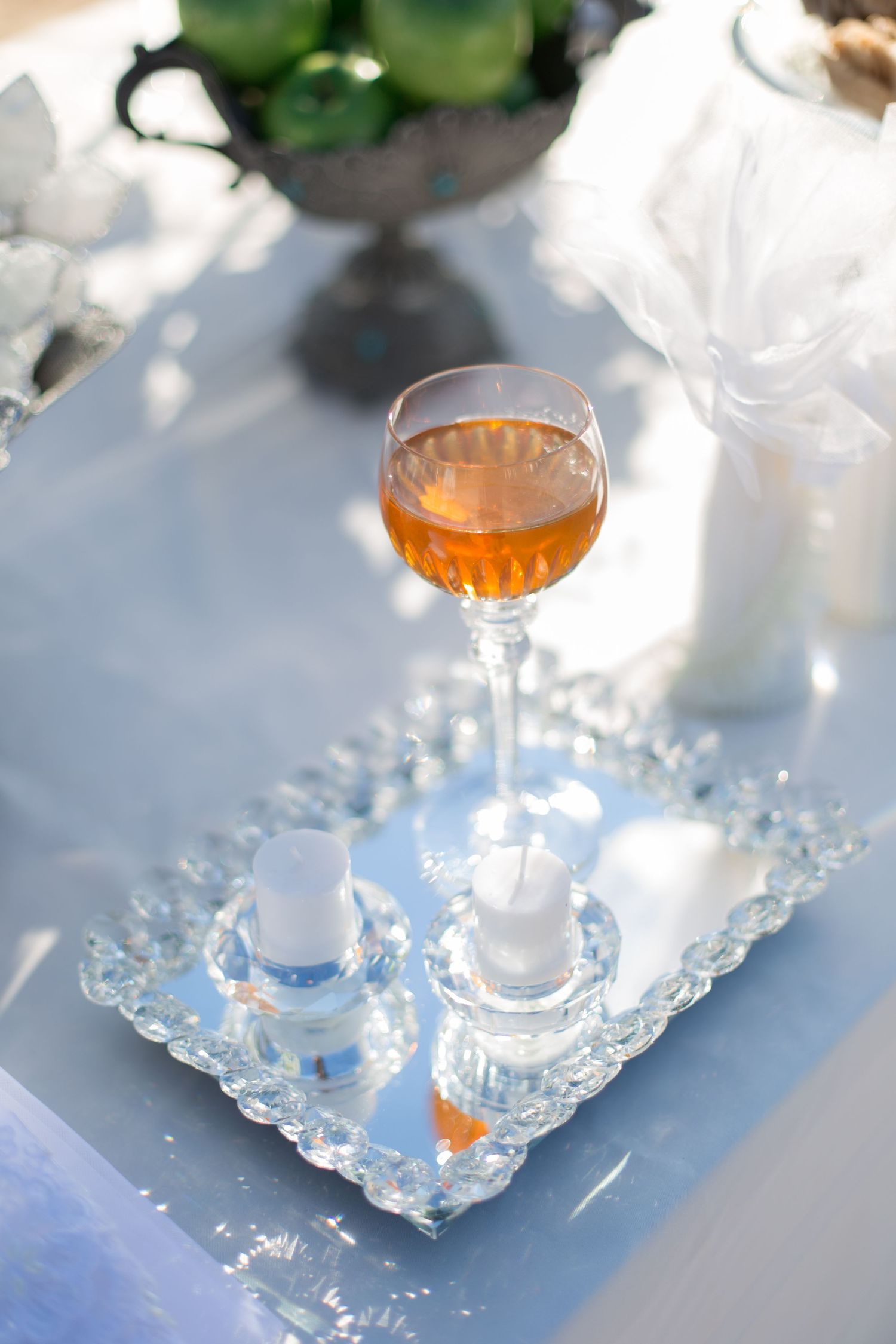 Glass of rose wine on a crystal tray in elegant wedding table setting.
