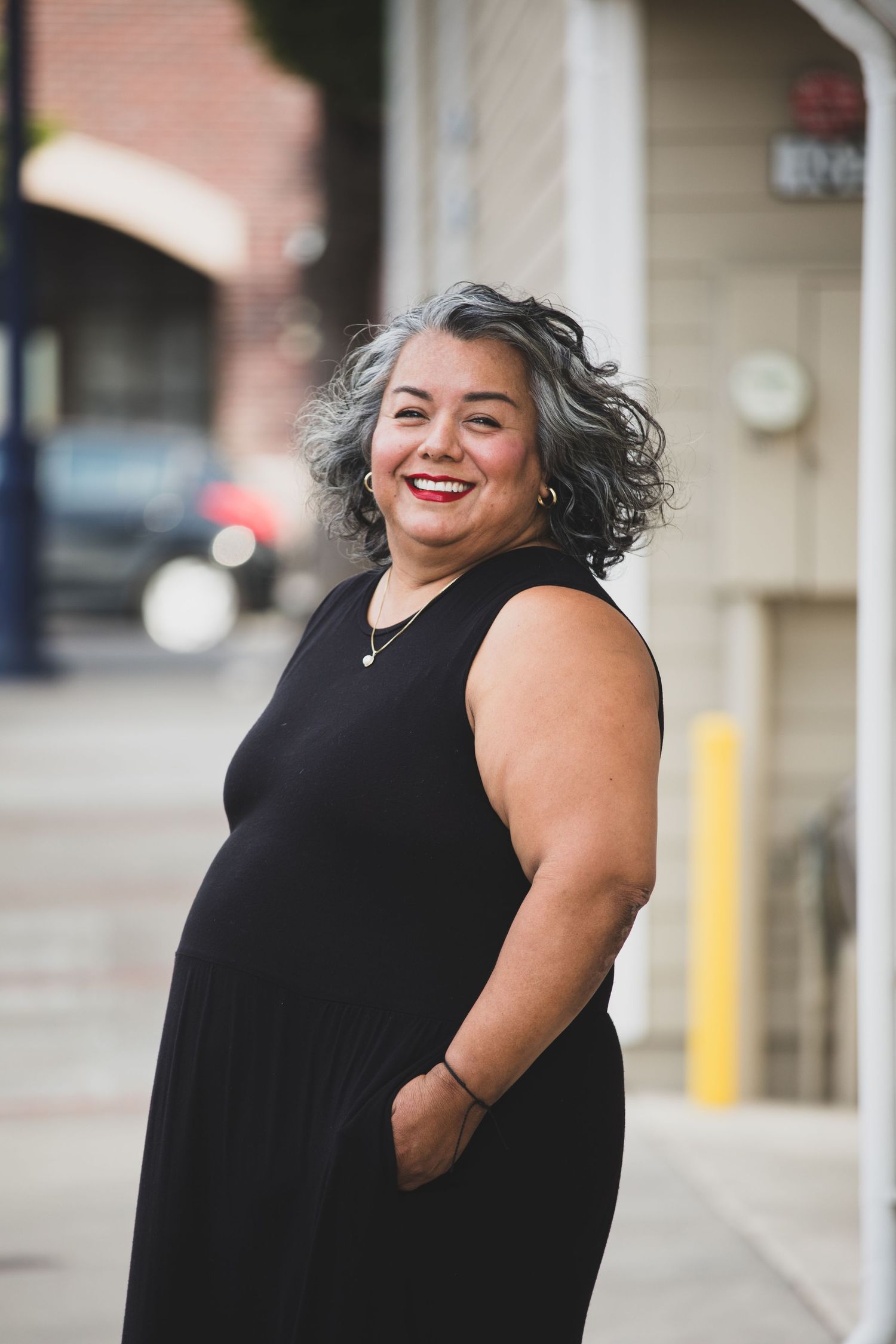 Series of candid portraits showing person in black sleeveless dress against brick building.