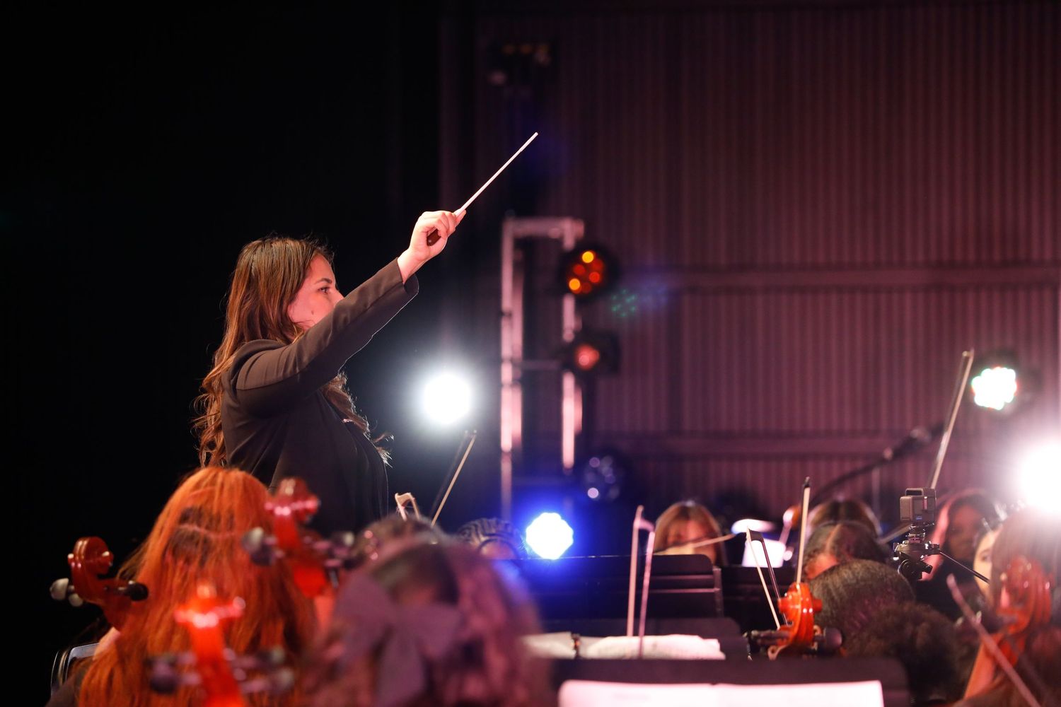 Conductor directing musicians with raised baton during orchestral performance.