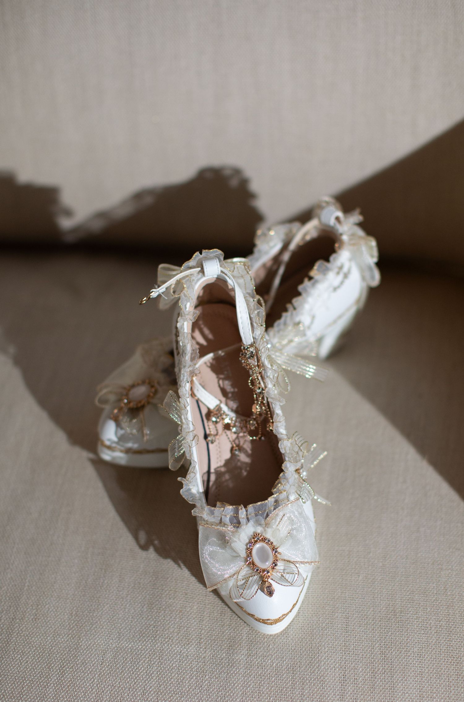 Delicate white lace wedding shoes with ornate details photographed in natural light.