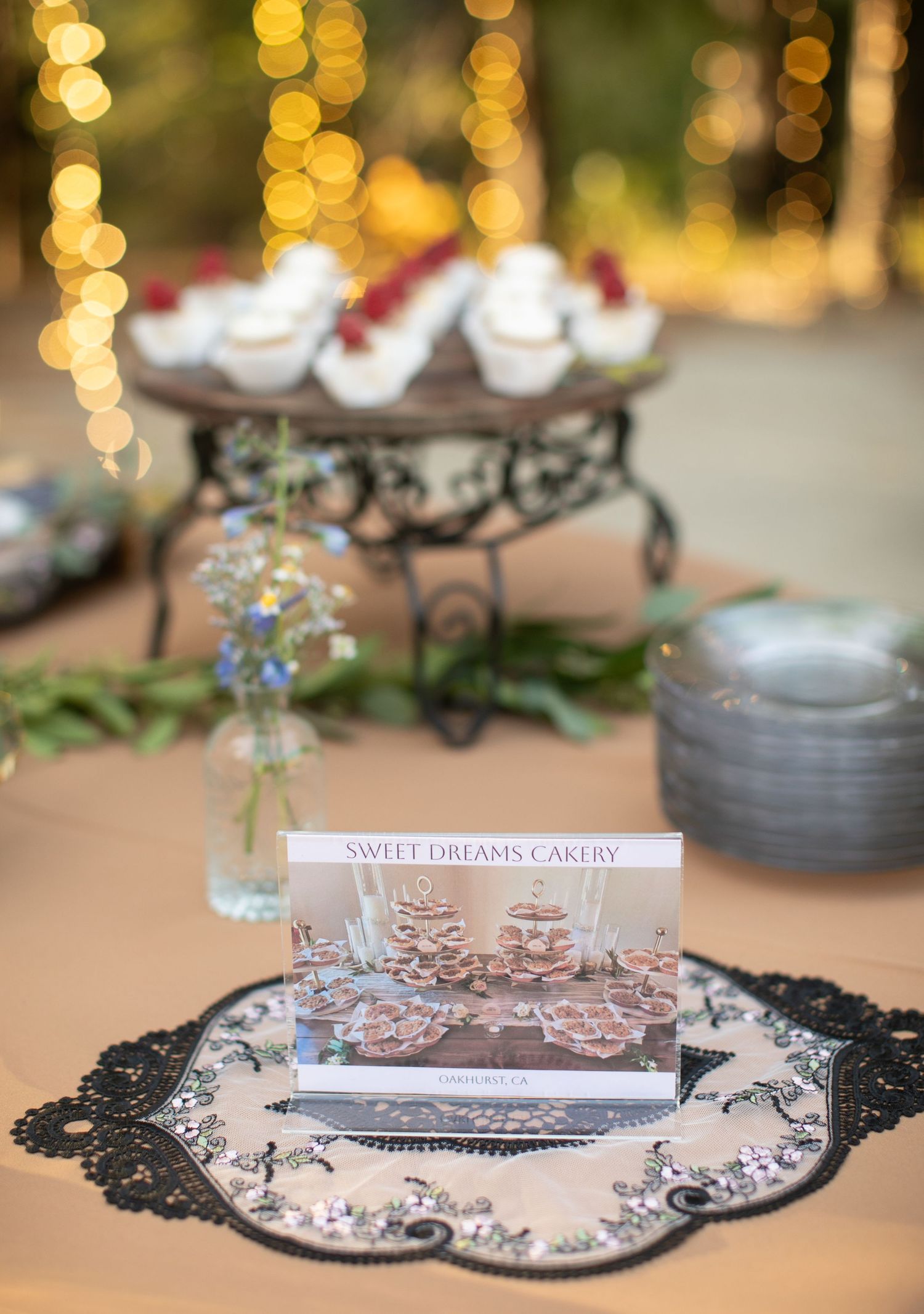 Wedding dessert table setup with decorative black lace doilies and Sweet Dreams Bakery signage.