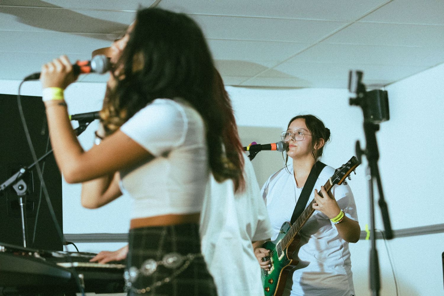 Musicians performing on stage in casual attire with guitars and microphones.