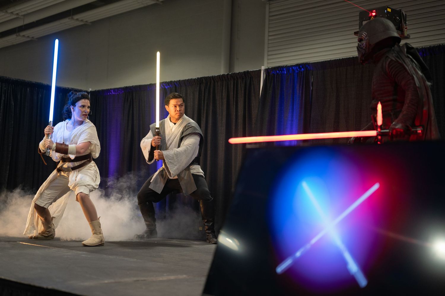 Two performers engage in dramatic lightsaber battle scene with glowing blue and red props.