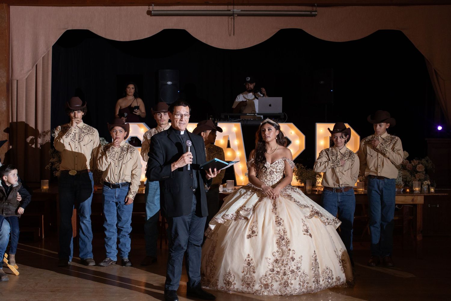 A formal celebration in a dimly lit venue with performers and a guest in an elegant gown.