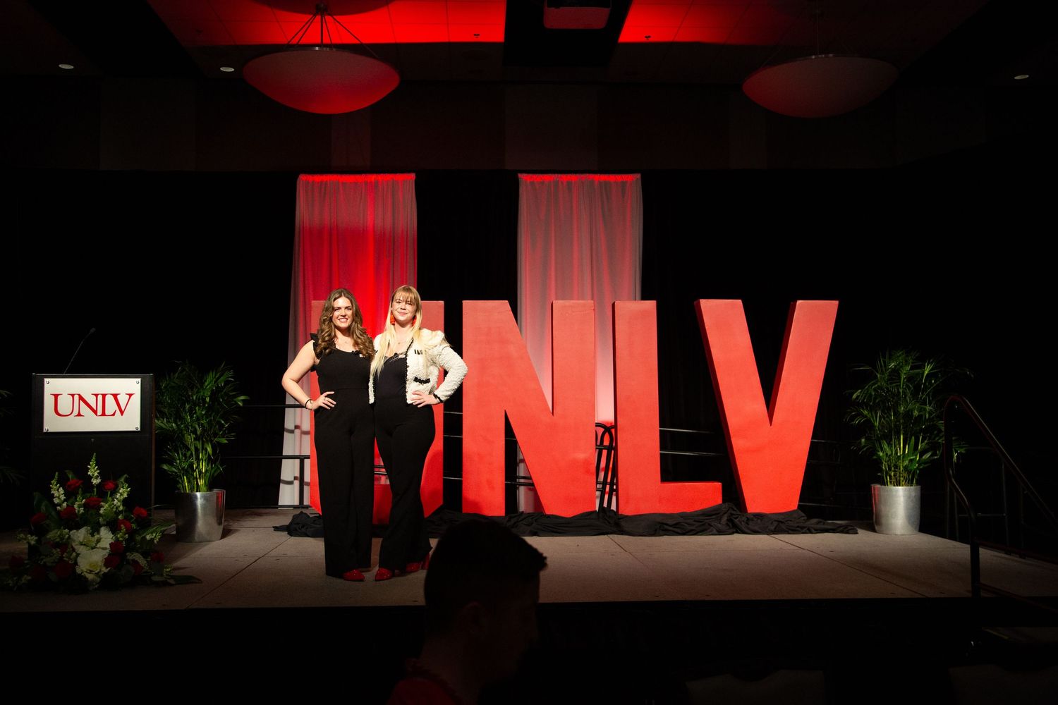 Stage presentation with large red UNLV letters illuminated in dramatic lighting.