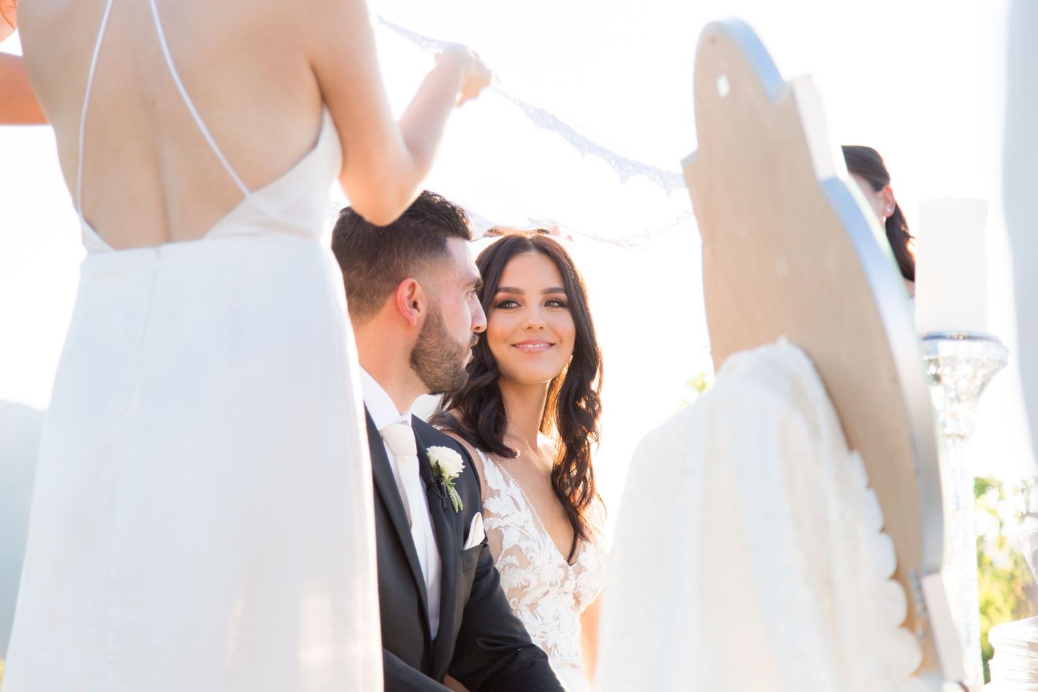 Candid wedding ceremony moment captured in warm sunlight with guests in background.