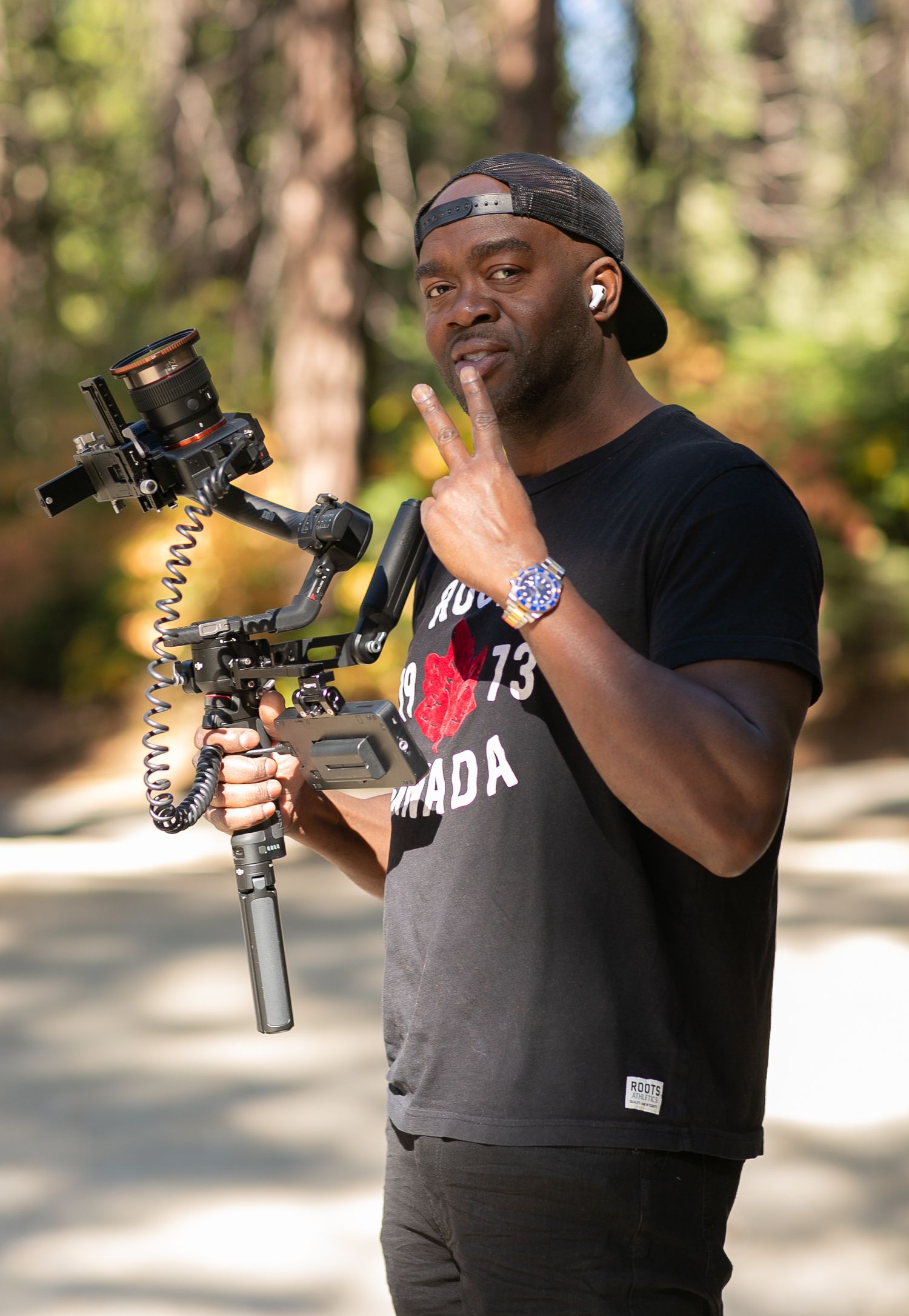 Videographer holding camera rig and gesturing while filming outdoors.
