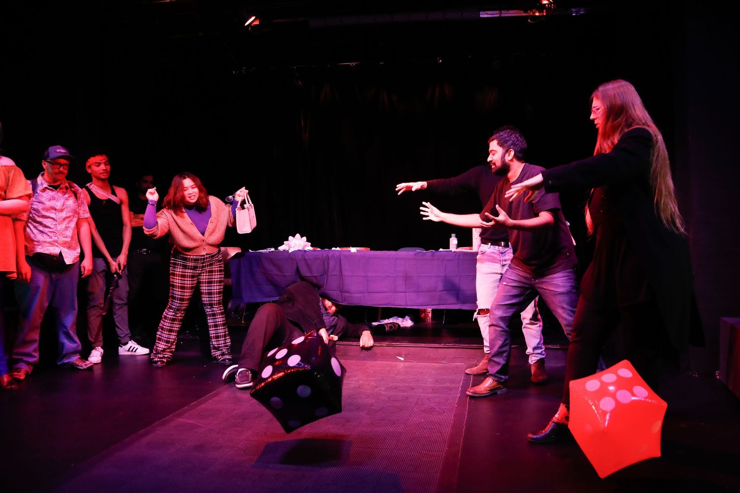 Performers engaged in dynamic stage movements under red theatrical lighting.