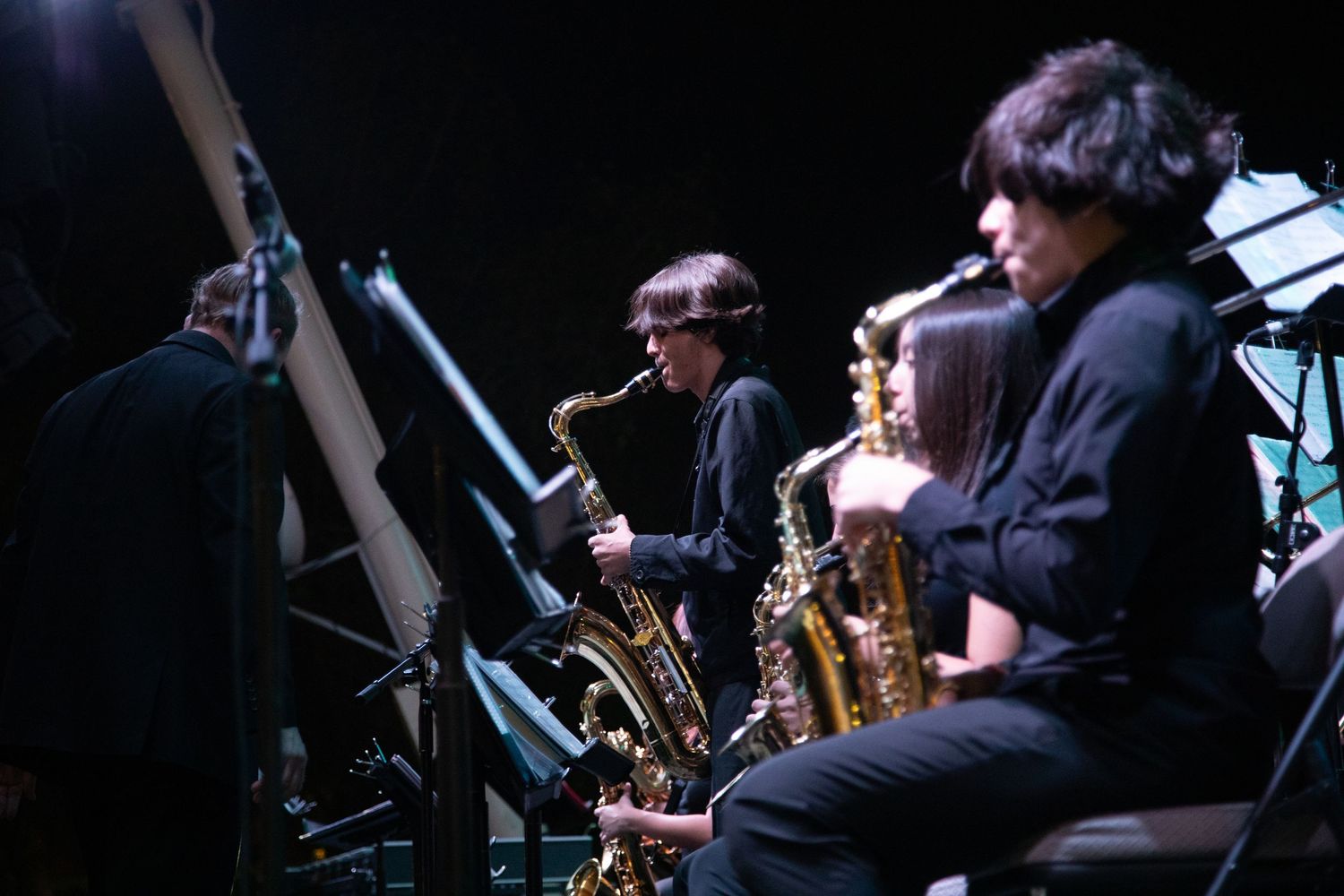 Jazz band saxophone section performs during nighttime concert.