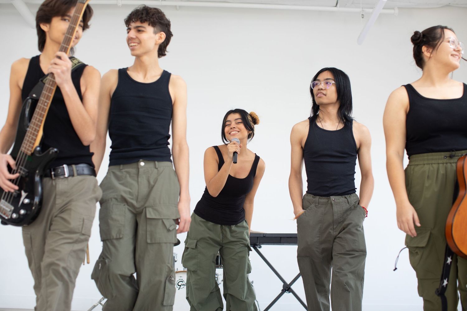 Musicians in coordinated outfits stand in line holding their instruments.